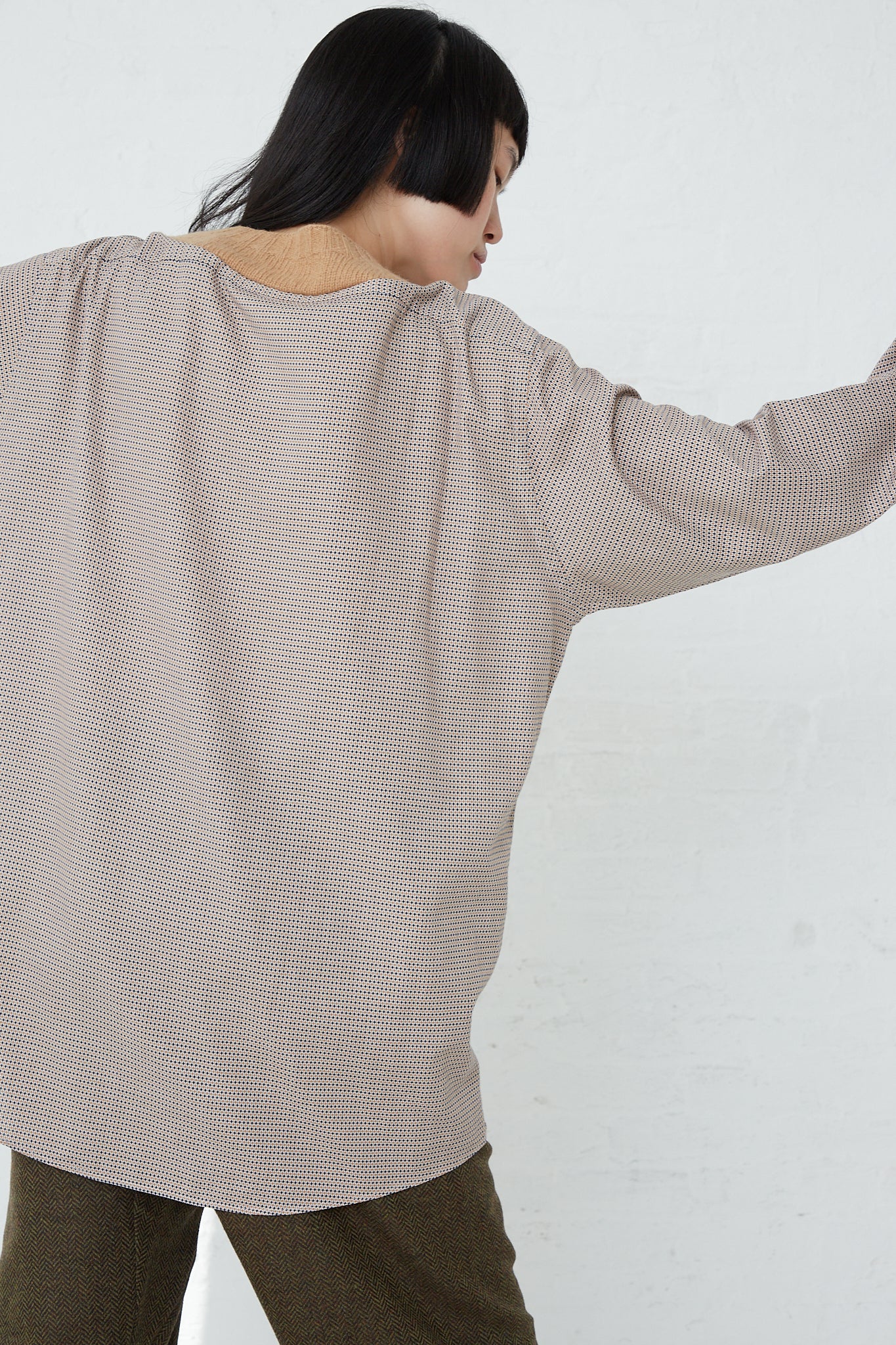 A woman wearing a long-sleeved Bless No. 68 Front Insert Pullover in Beige Pattern made of Shetland wool.