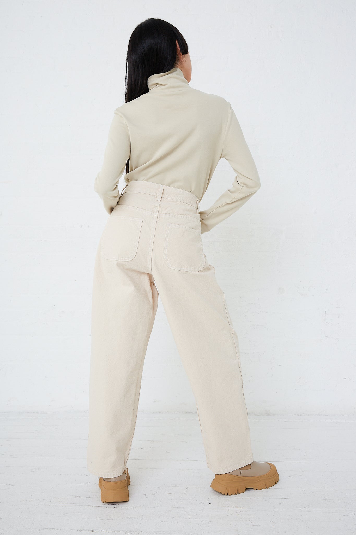 The back view of a woman wearing Jesse Kamm's Organic Canvas California Wide pants in Natural.