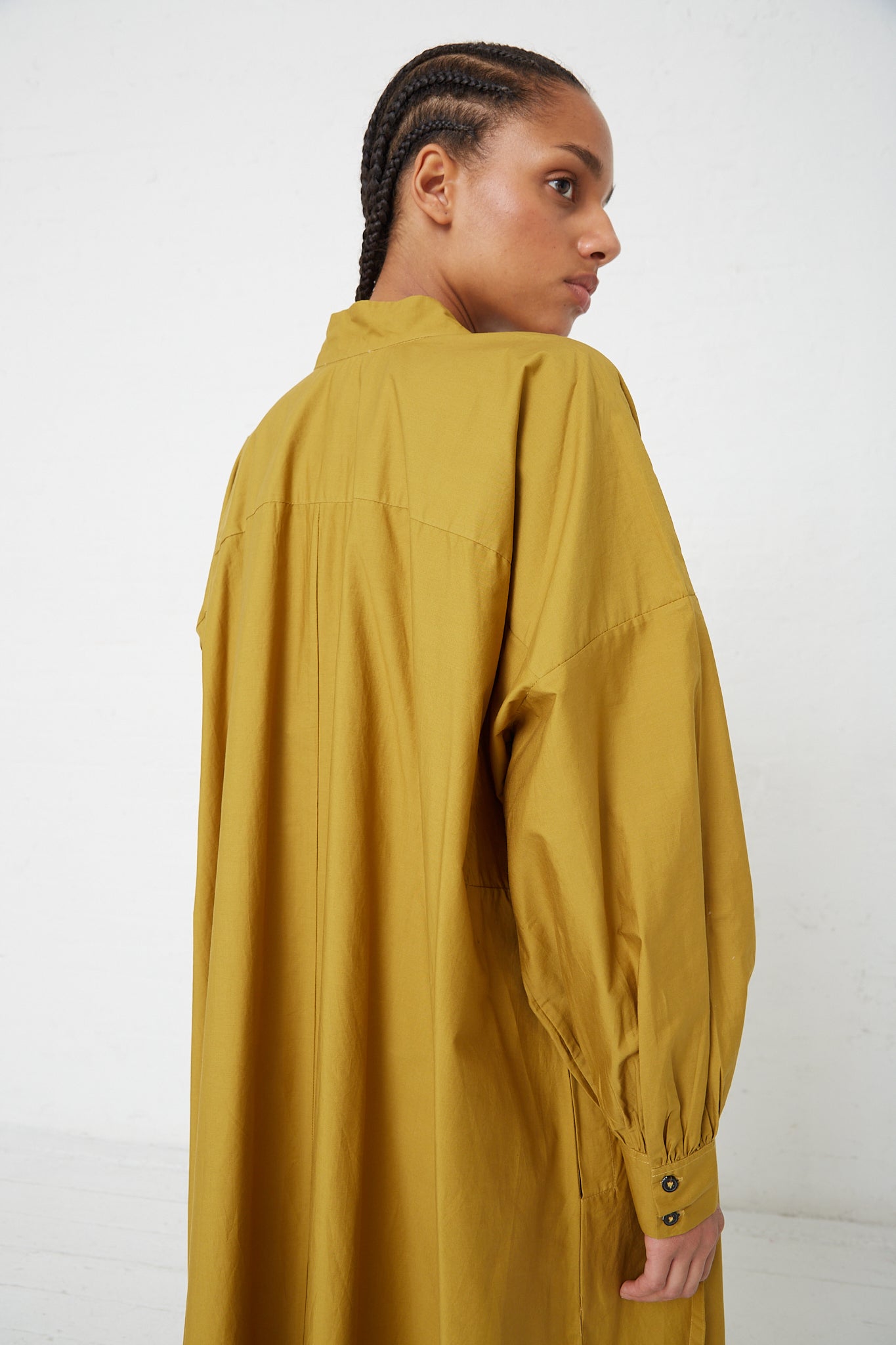 The back view of a woman wearing a Rachel Comey Bridge Dress with Hearts Eyelet in Chartreuse with a drawstring tie waist.