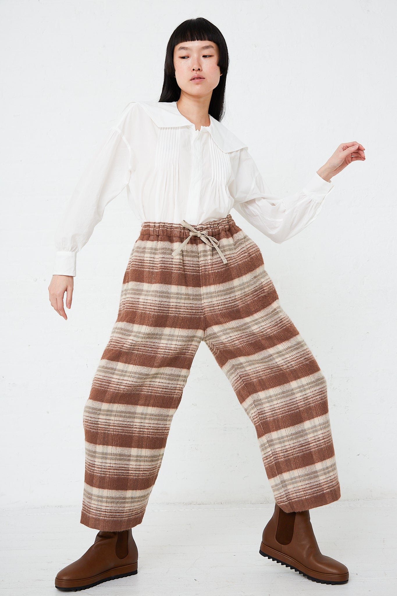 A woman in Silk Plaid Mosser Cloth Pajama Pants in Cocoa Brown by Toujours is posing for a photo.