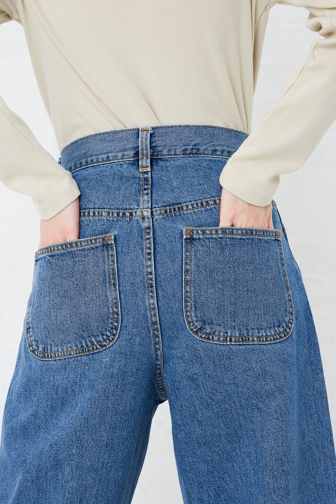 The back view of a woman wearing a pair of Jesse Kamm Japanese Denim California Wide jeans in Cowboy Blue with pockets, embodying the essence of a minimalist wardrobe.