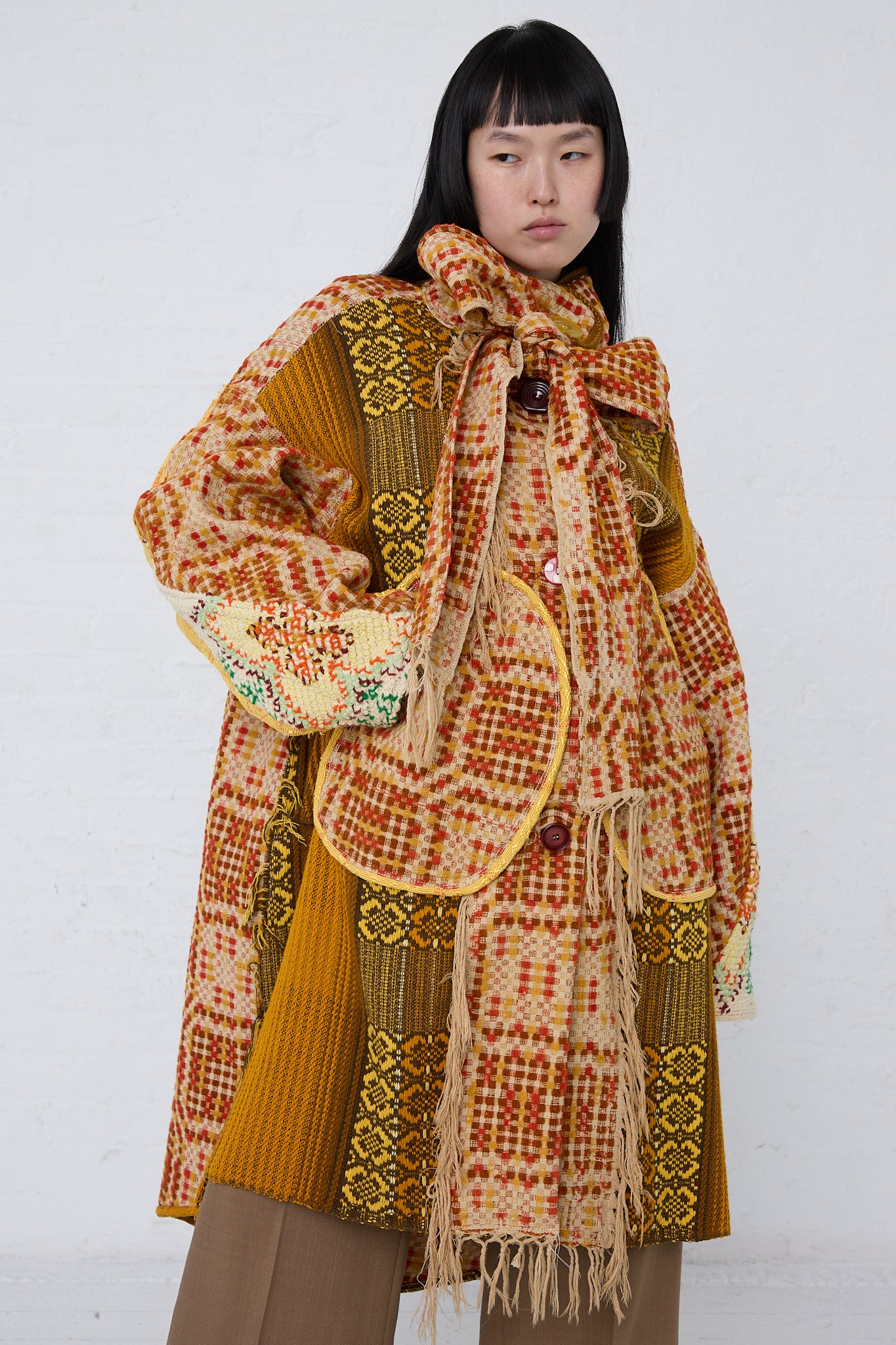 A woman wearing a Thank You Have A Good Day Patchwork Blanket Scarf Parka in Red, Yellow and Brown. Full-length, front view.