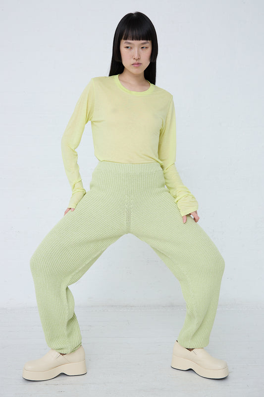 A woman in Baserange's Cotton Dodd Pant in Mimosa is posing in front of a white wall.