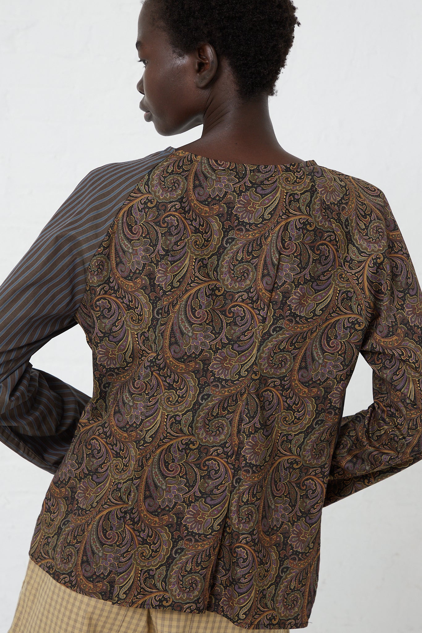 The back view of a woman wearing a brown Paisley Poplin Peak Blouse in Ornament by SC103.
