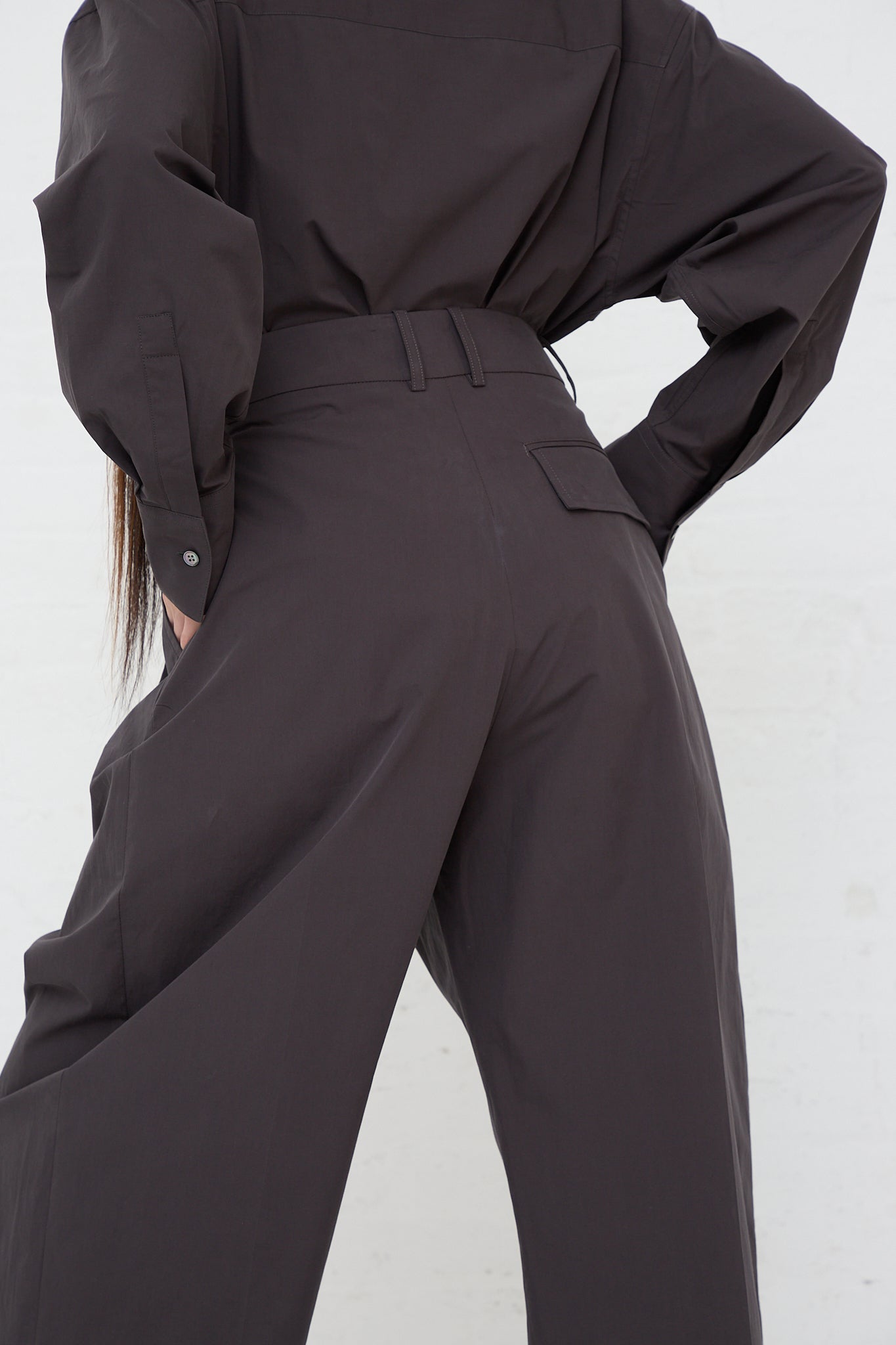 The back of a woman wearing Studio Nicholson's Acuna Double Pleat Front Trouser in Asphalt made of powder cotton.