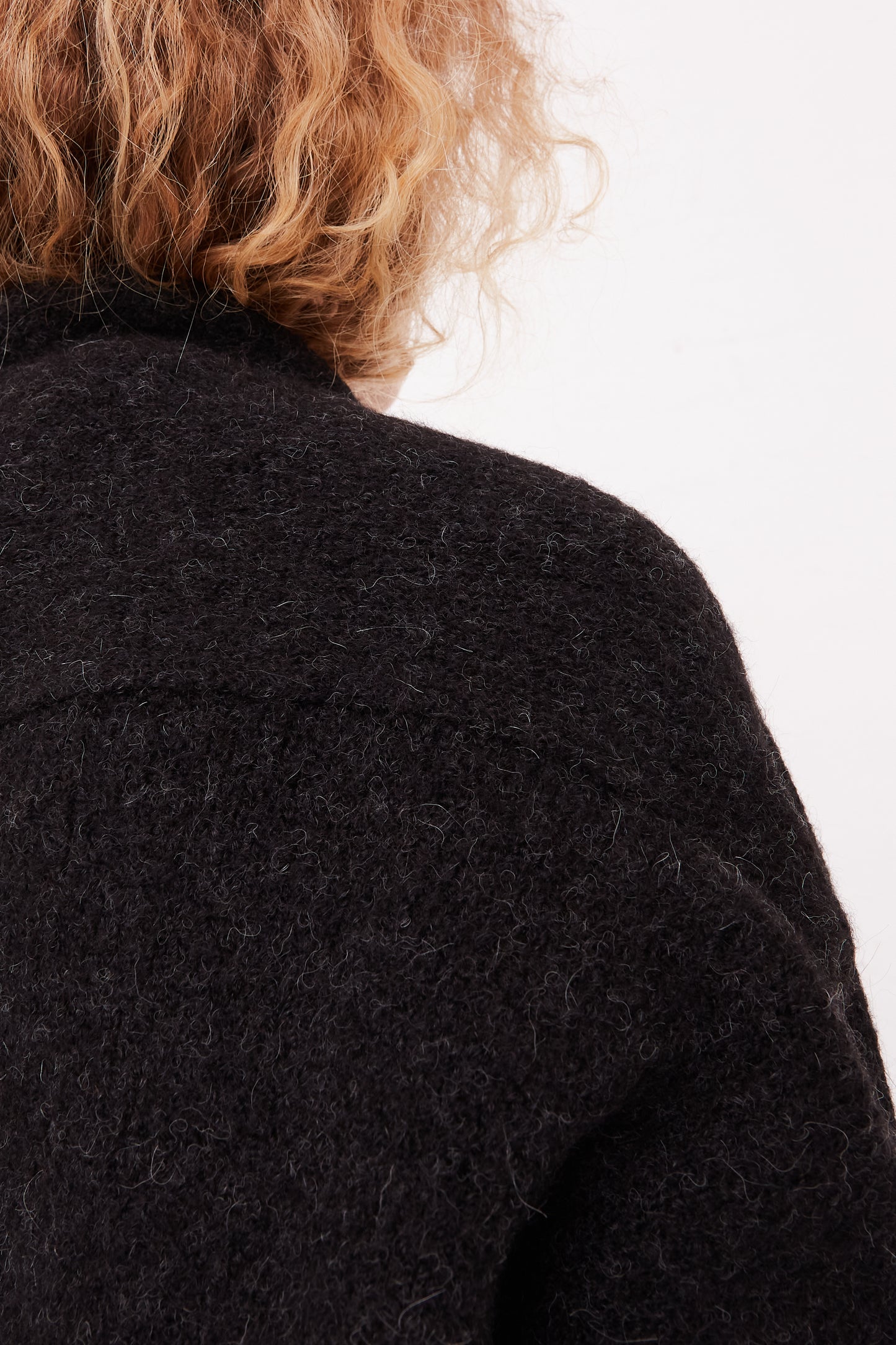 The back view of a woman wearing a Lauren Manoogian Long Shawl Cardigan in Black.