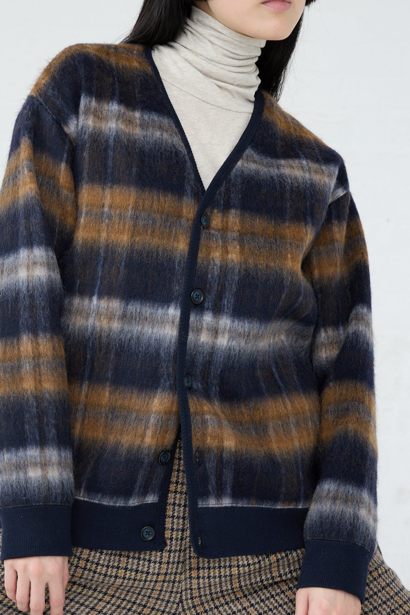 The model is wearing an Ichi Knit Cardigan in Navy, featuring a v-neck and shades of blue and brown. Up close. 