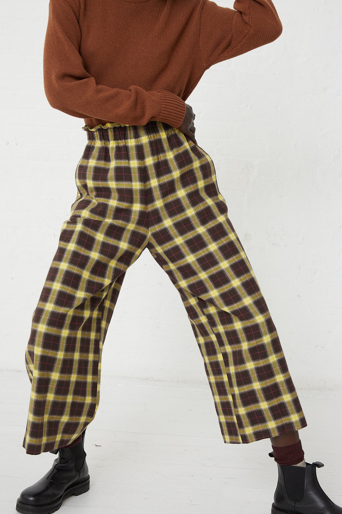 A woman wearing a brown sweater and AVN Easy Pant in Check Brown, Yellow and Pink with a relaxed fit.