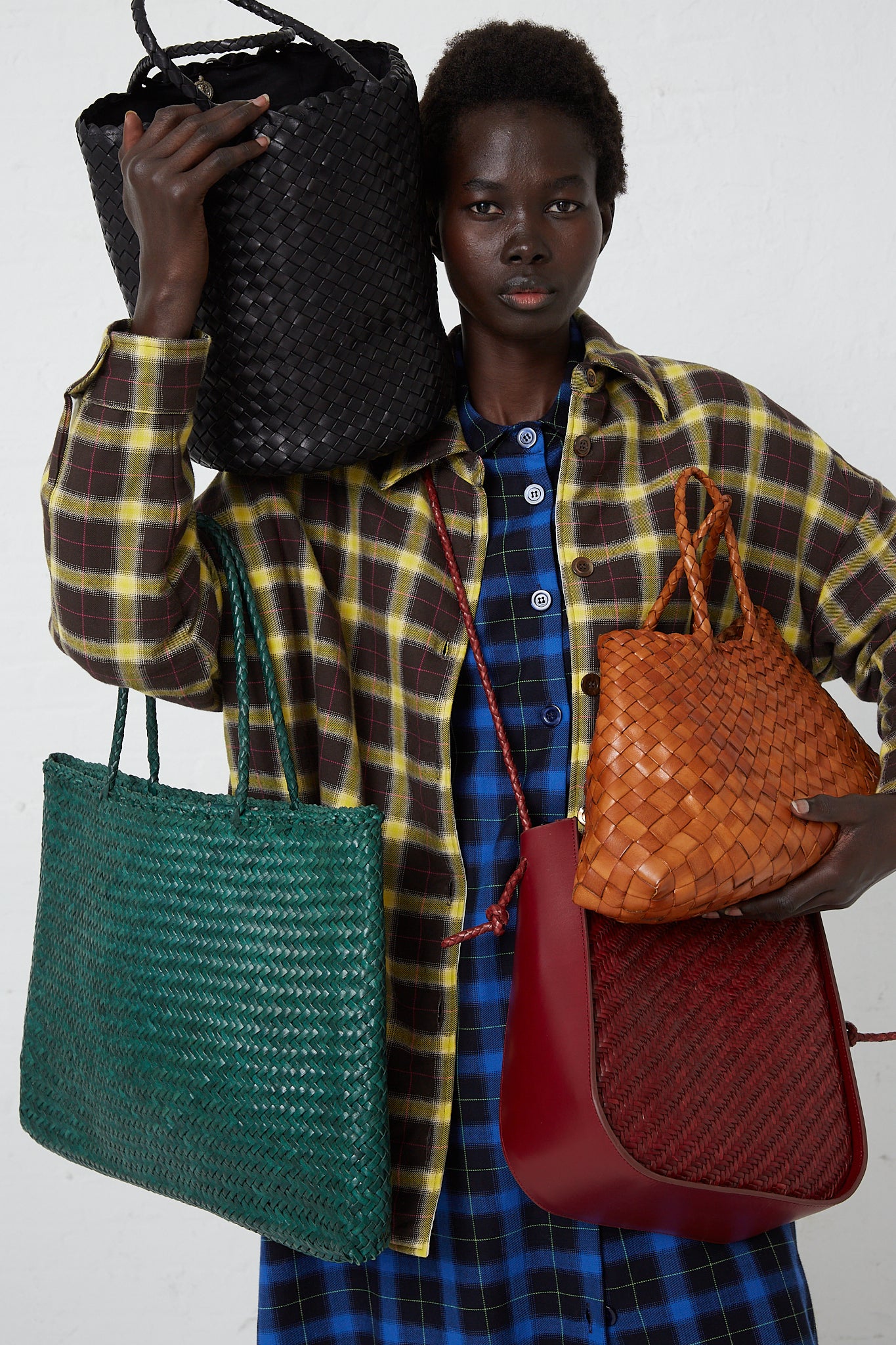 A woman in plaid shirt showcasing an assortment of Dragon Diffusion bags. 