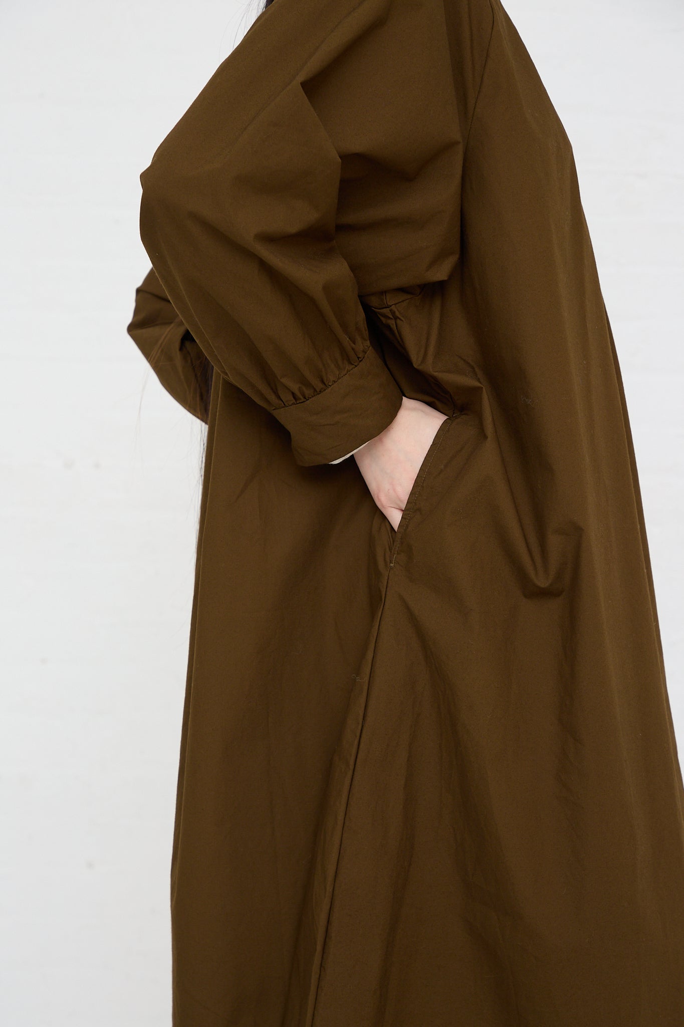 A woman wearing an Ichi Woven Cotton Dress in Seal Brown with pockets. Side view.