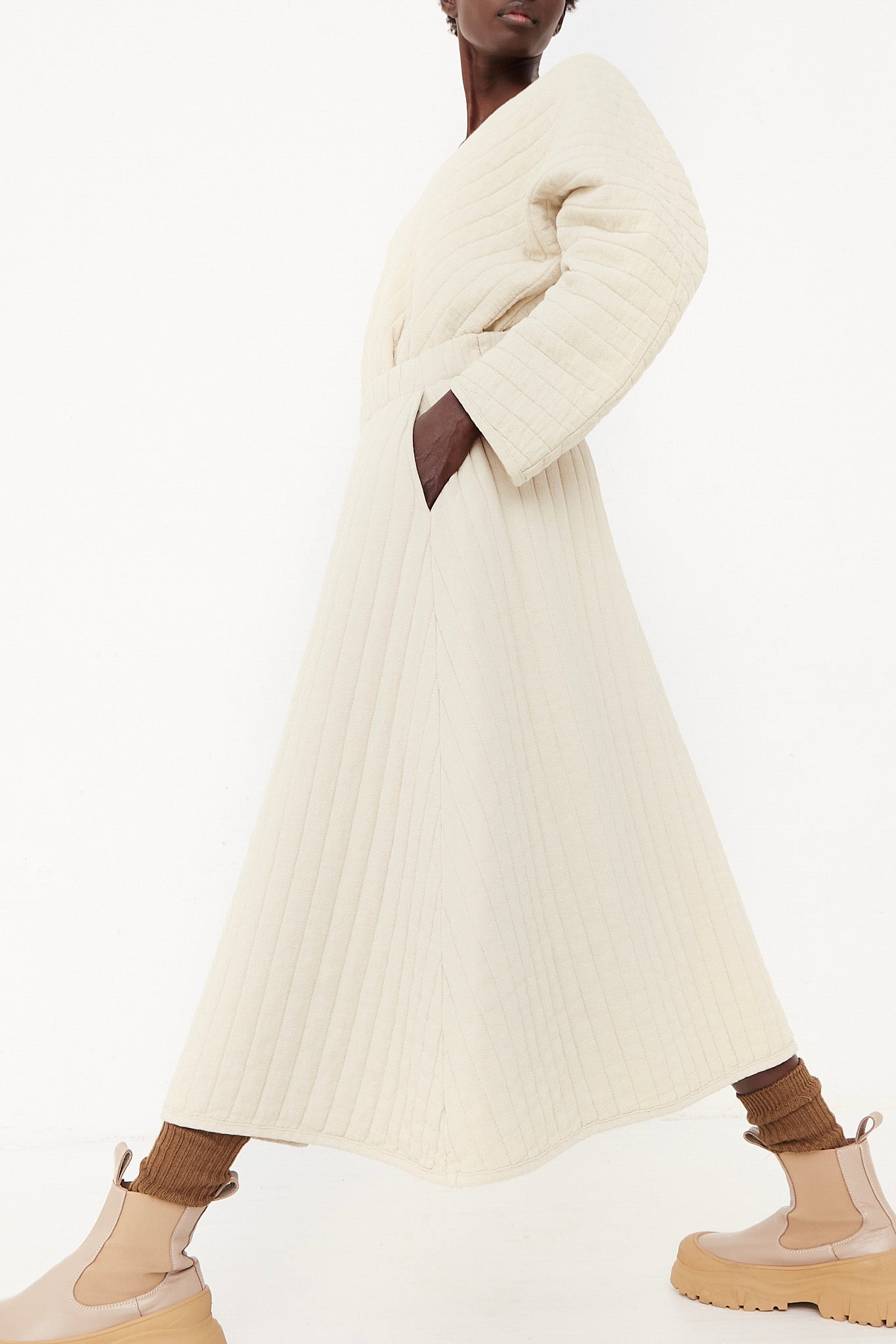 The model is wearing an ivory Black Crane quilted sweater dress.
