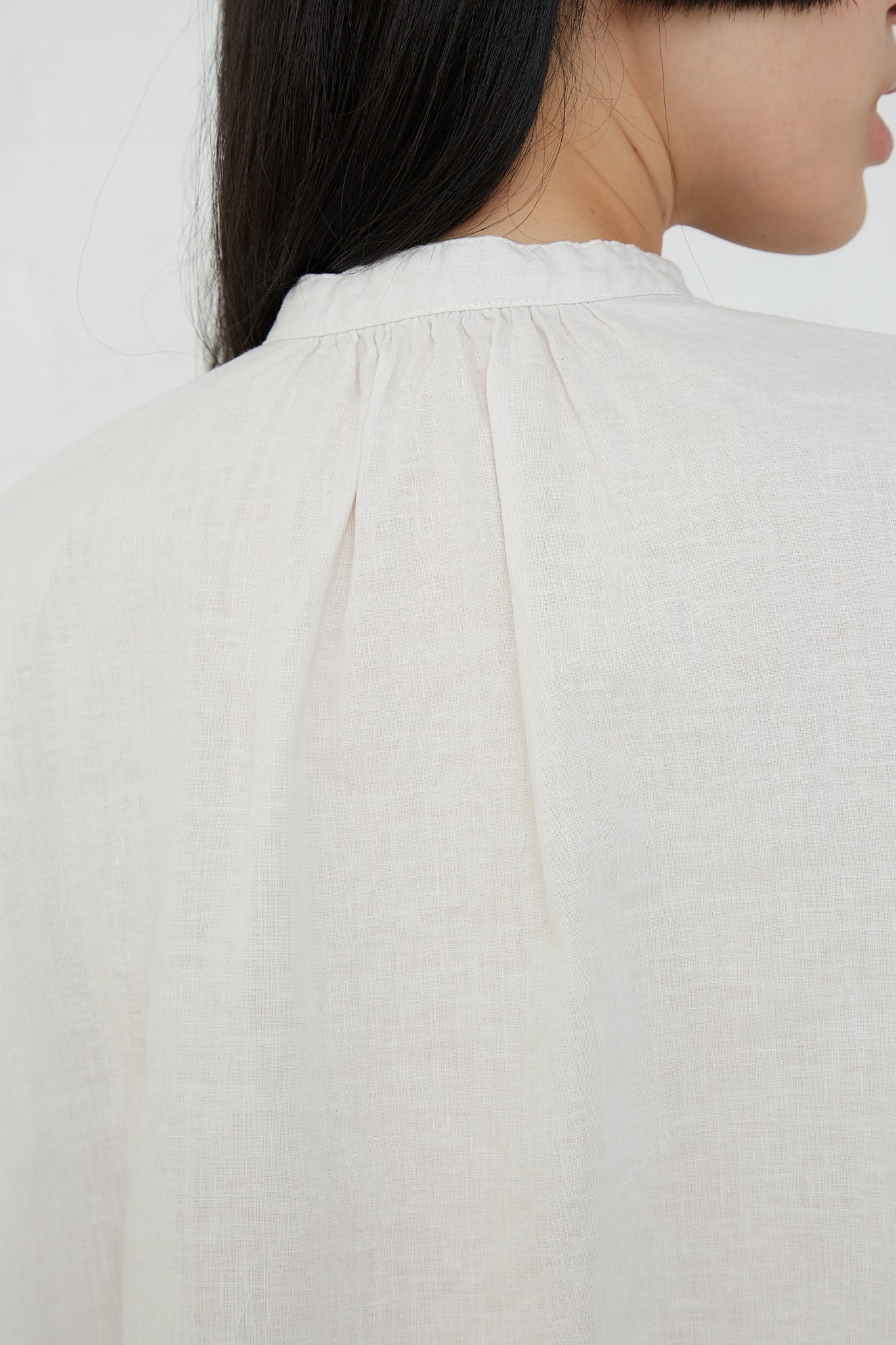 The back view of a woman wearing a nest Robe UpcycleLino Linen Gathered Frill Blouse in Off White.