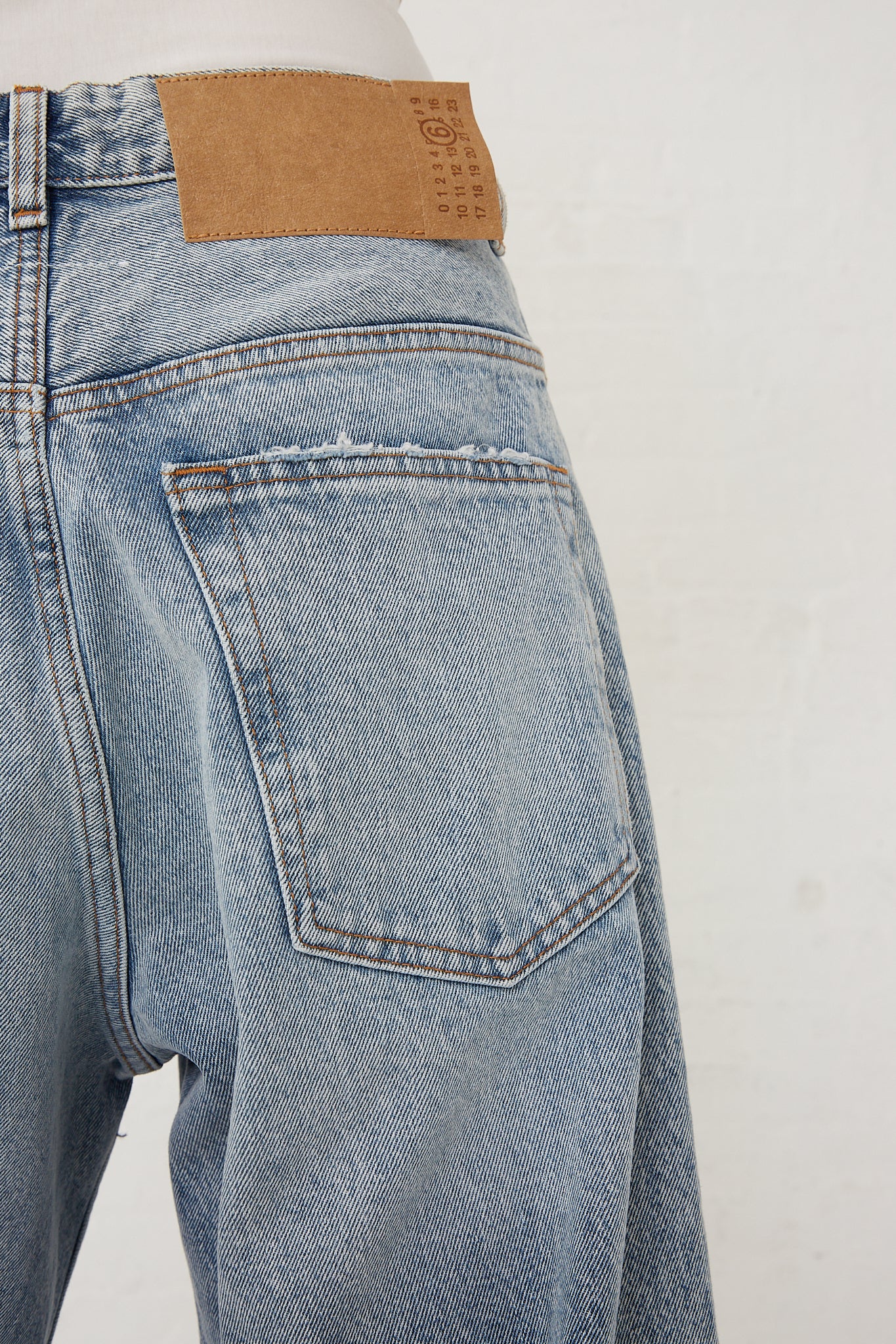 The back of a woman's MM6 light indigo denim shorts featuring a classic 5-pocket design.