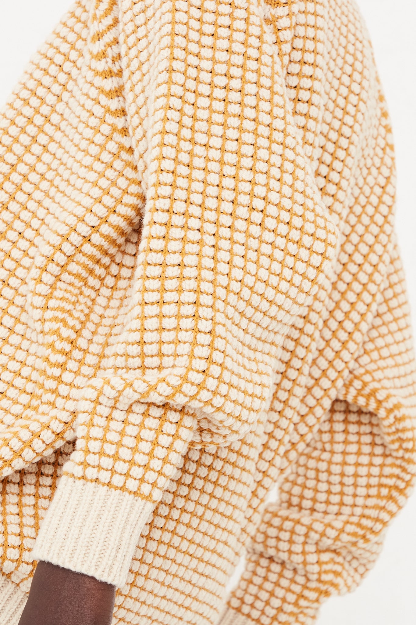 The back view of a woman wearing an oversized yellow and white checkered Crewneck Sweater made with merino wool in Natural Gold Lalin by Jan-Jan Van Essche.
