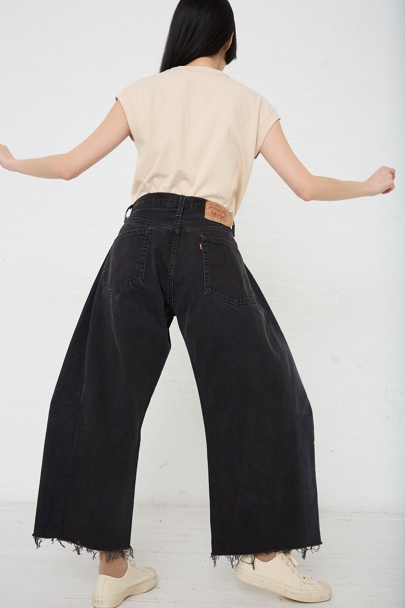 A woman is donning a pair of B Sides' Lasso in Vintage Black denim wide leg pants with a slouchy fit.