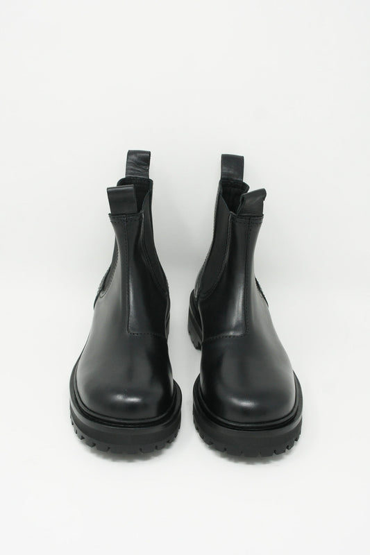 A pair of Studio Nicholson Kick Boots in Black, made of Italian calf leather with a Vibram rubber sole, photographed on a white background.