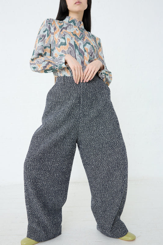 A woman wearing Mina Perhonen's Predawn Trouser in Navy Mix made in Japan and a floral blouse with a relaxed fit.