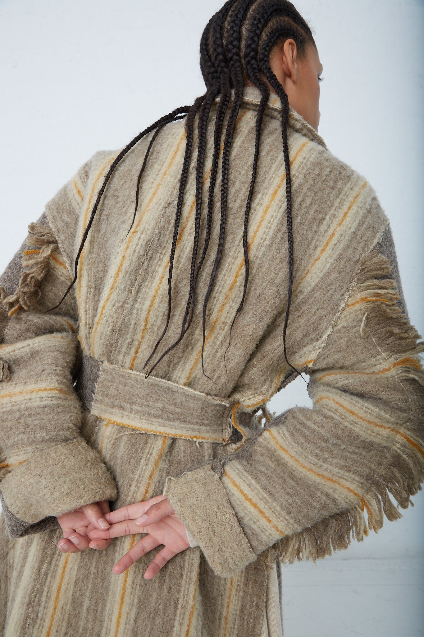 A woman wearing a Thank You Have A Good Day Wool Blanket Swing Trench coat with fringes. Back view. Up close.