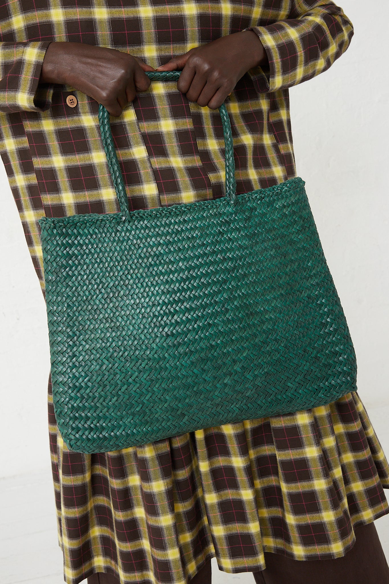 A woman is holding a Sophie Large Tote Bag in Forest, skillfully handwoven using traditional techniques by Dragon Diffusion.