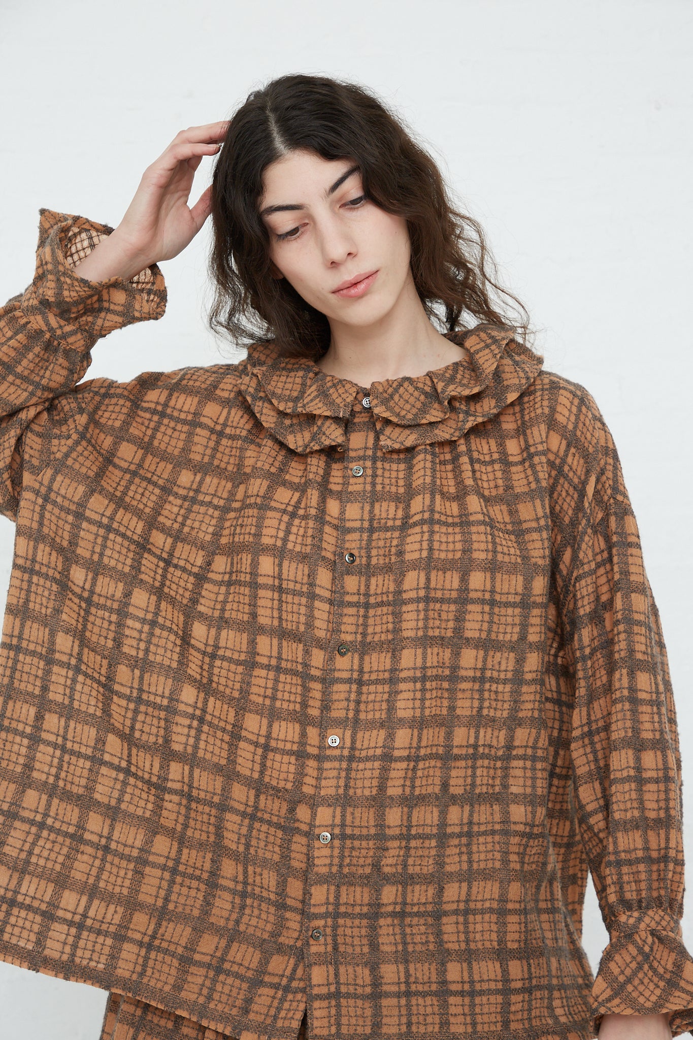 The model is wearing a Ichi Antiquités Wool Check Frill Blouse in Terracotta.