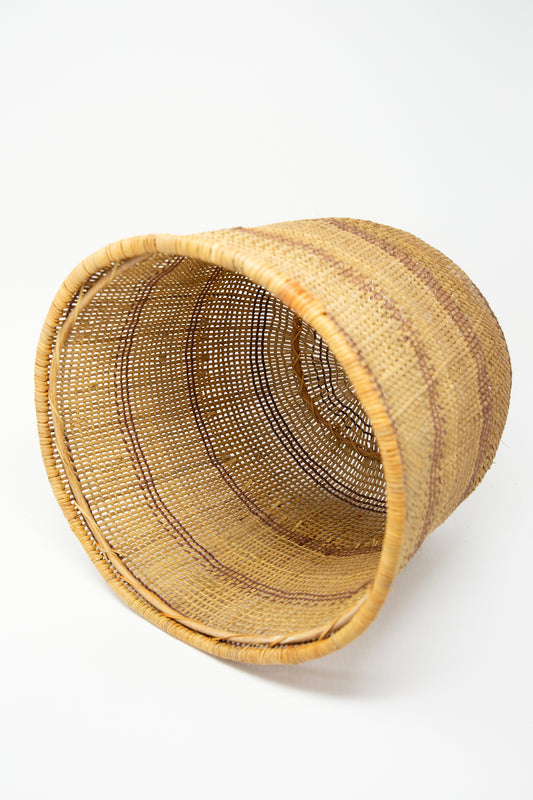 A Plaza Bolivar Medium Nukak Makú Basket, woven with bejuco yaré and dyed using natural dyes, placed on a white background.