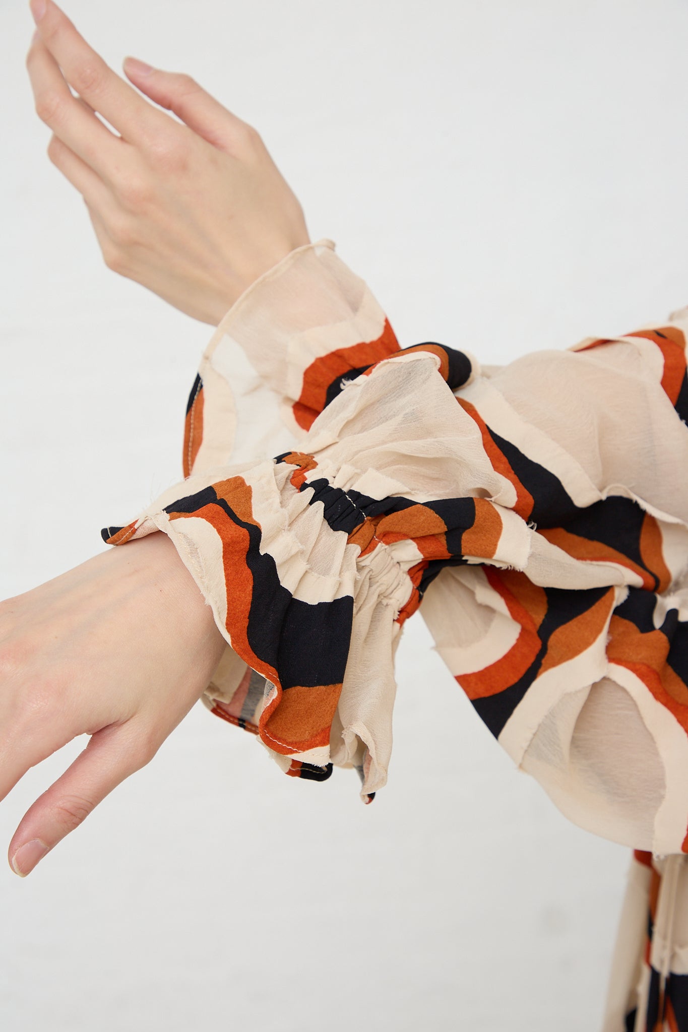 A woman wearing an Ulla Johnson black and orange patterned Echo Dress in Conch. Up close view of sleeves.