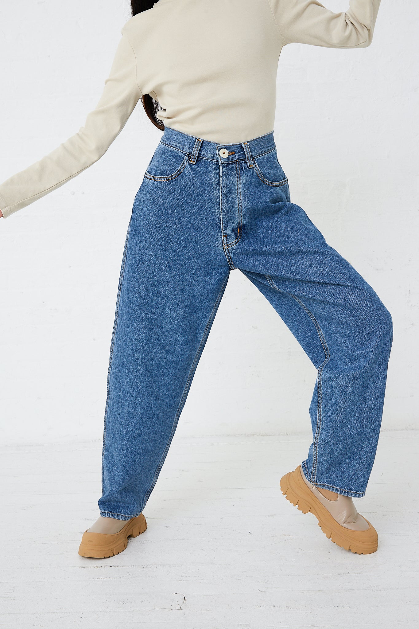 A woman wearing high waisted jeans made from Jesse Kamm's Japanese Denim California Wide in Cowboy Blue and a turtle neck sweater.