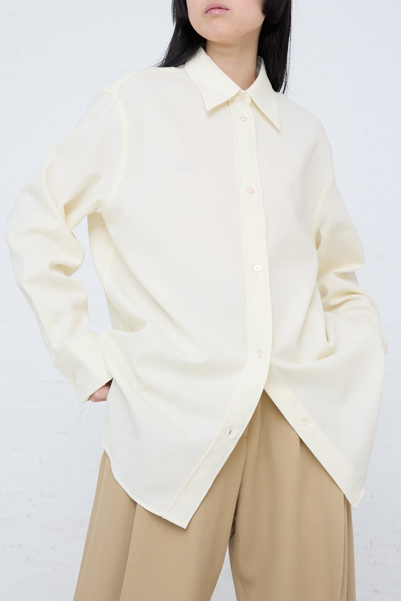 A woman wearing a Studio Nicholson Santos Overshirt in Parchment and tan pants.