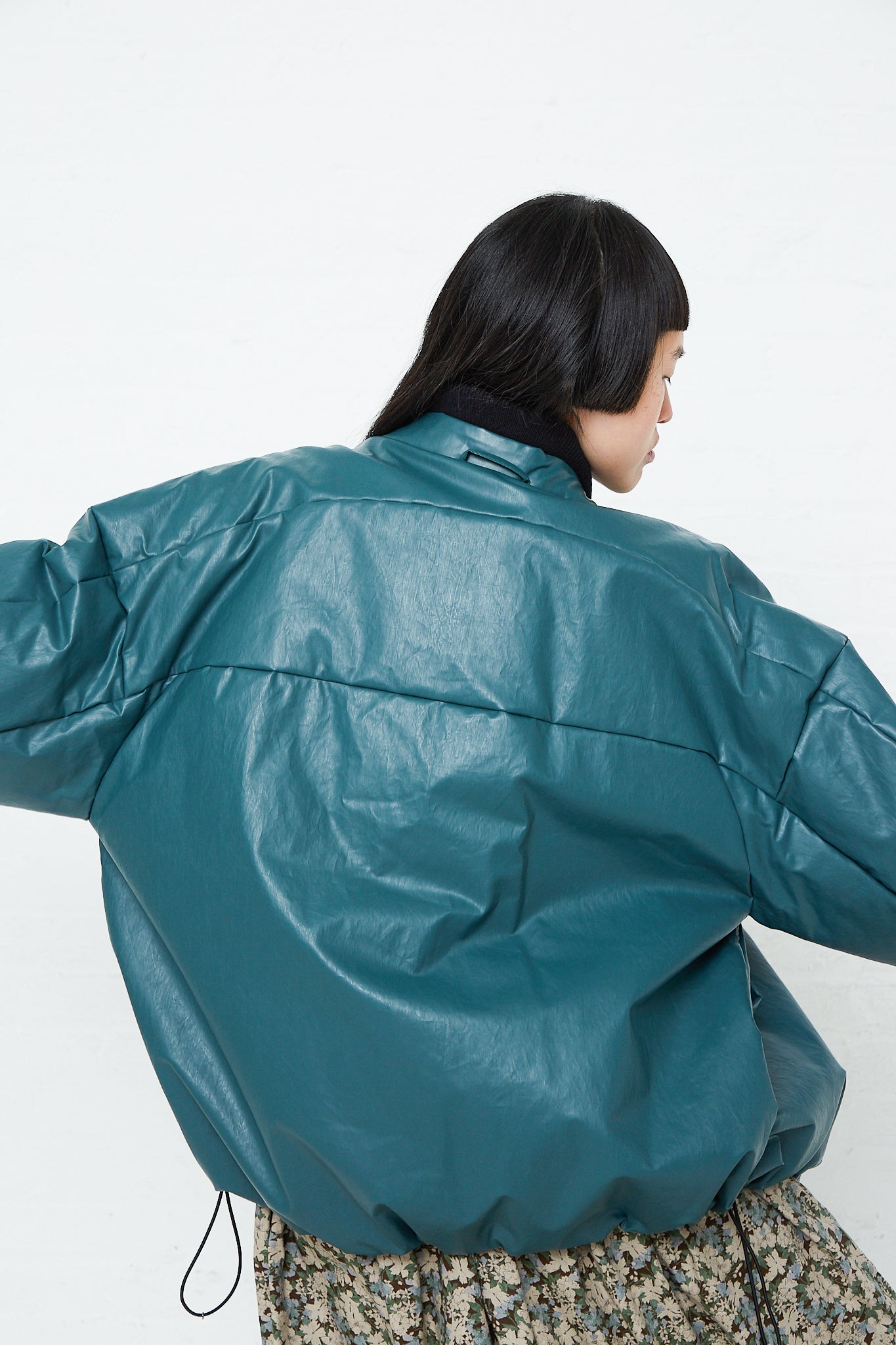 The back of a woman wearing an Kassl Oversized Padded Bomber Oil Jacket in Forest.
