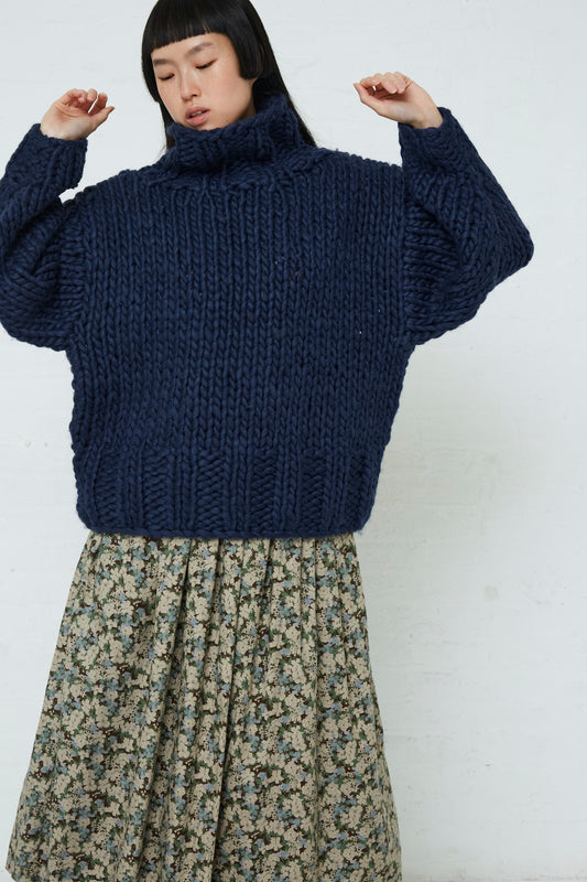 A woman wearing an oversized Ichi wool hand-knit pullover in navy and a floral skirt.