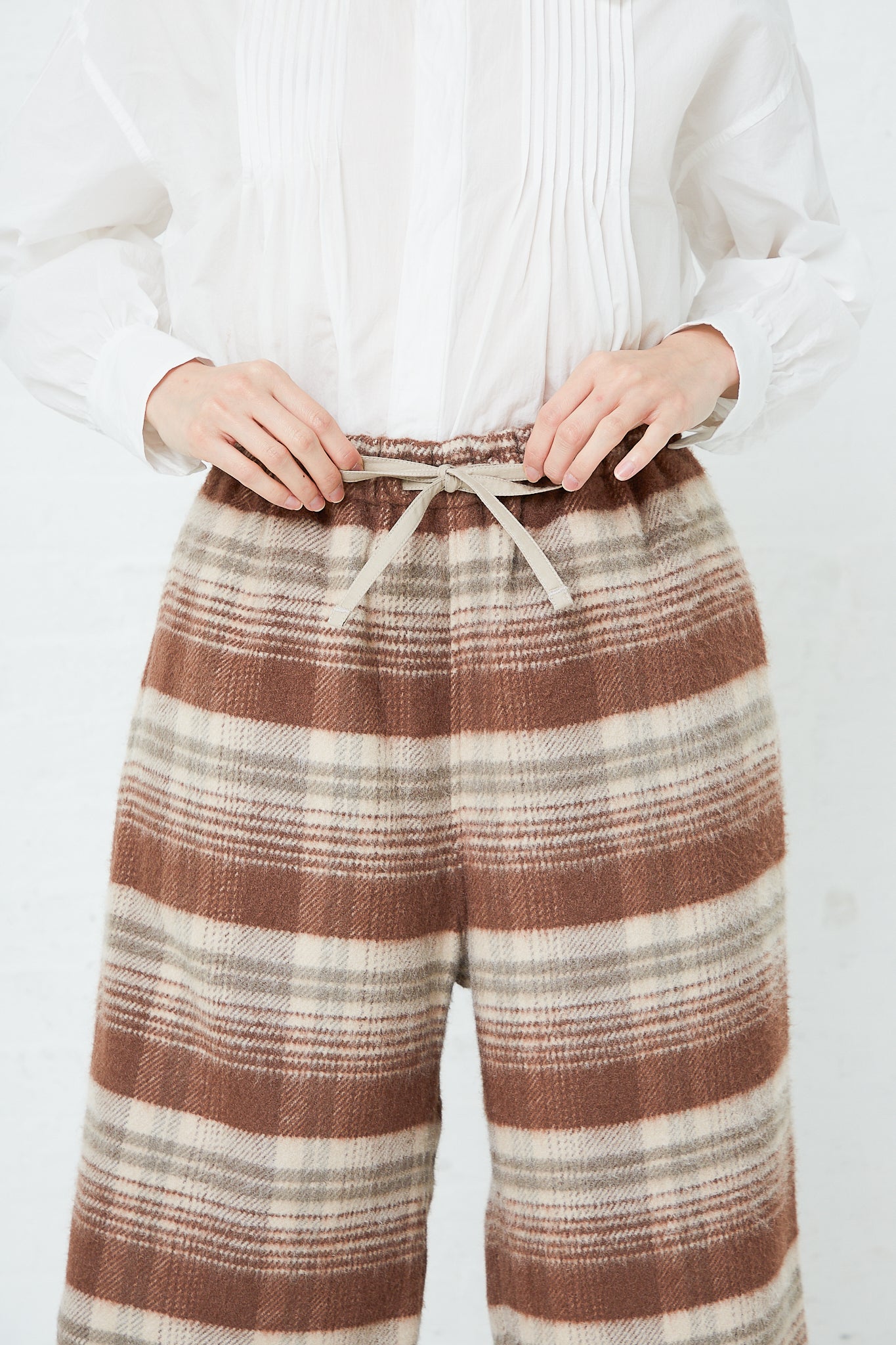 A woman wearing Toujours' Silk Plaid Mosser Cloth Pajama Pants in Cocoa Brown. Available at Oroboro Store.