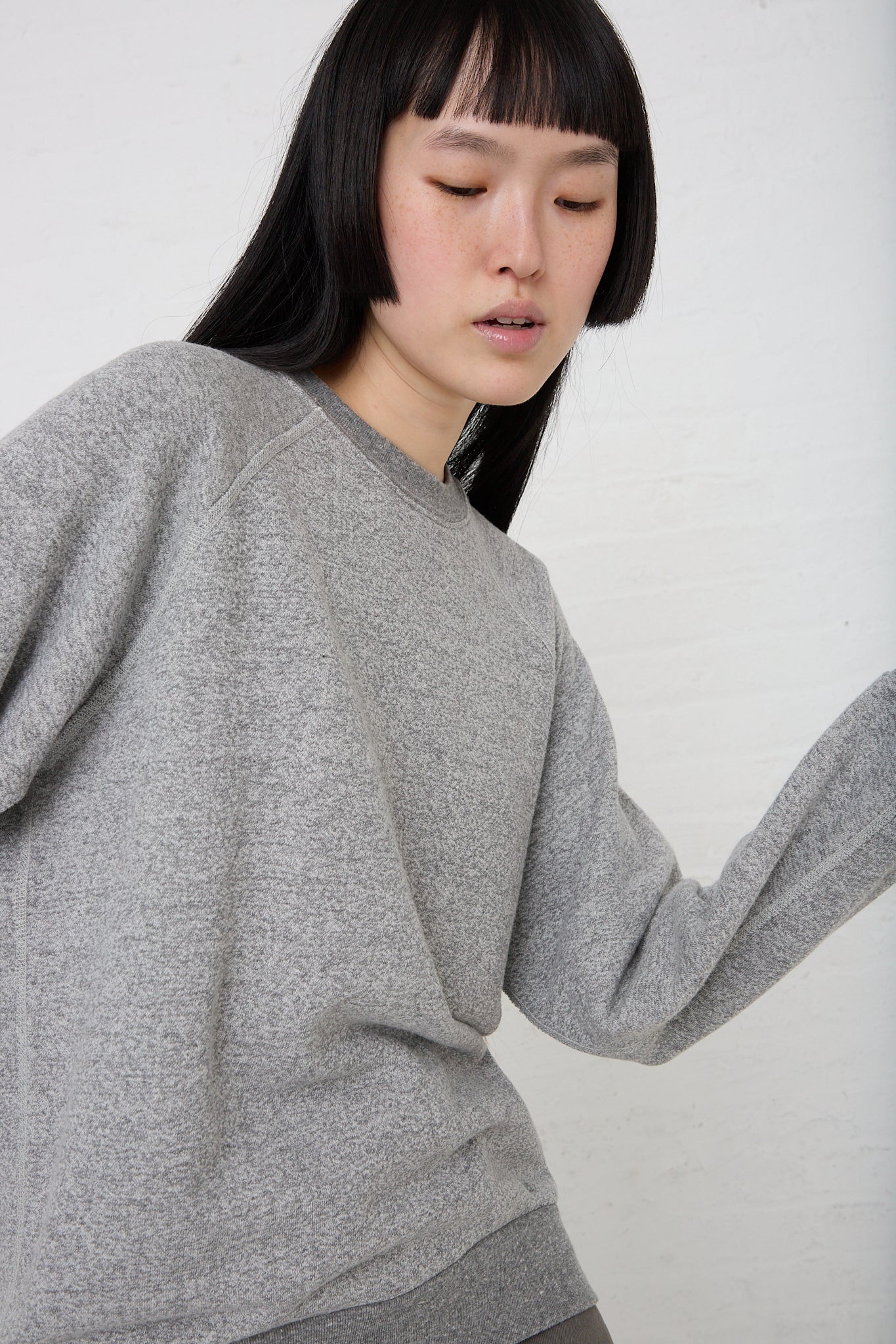 The model is wearing a French Terry Sweatshirt in Heather Grey by B Sides.
