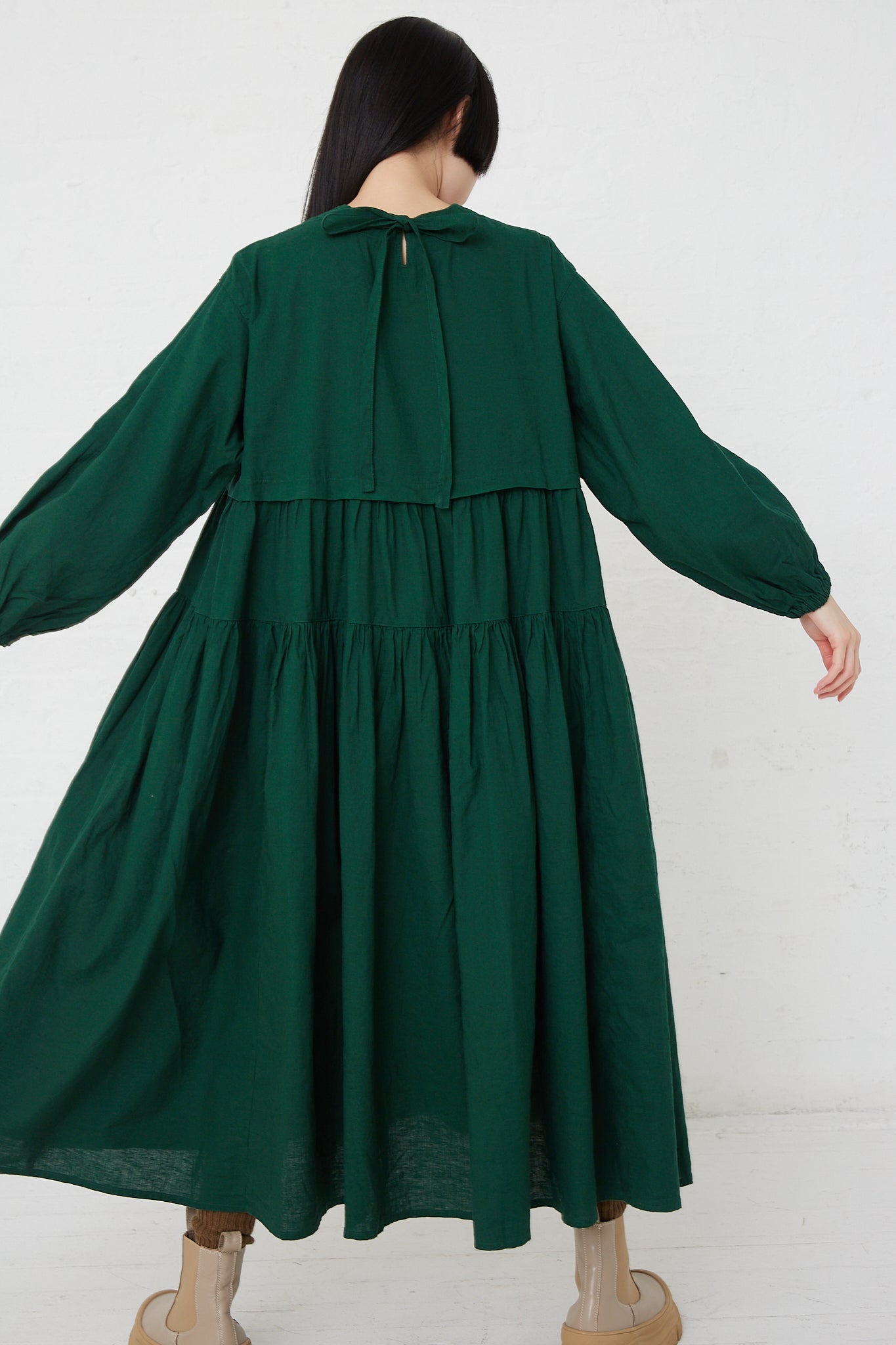 The back of a woman wearing the UpcycleLino Linen Tiered Gather Dress in Green by nest Robe.
