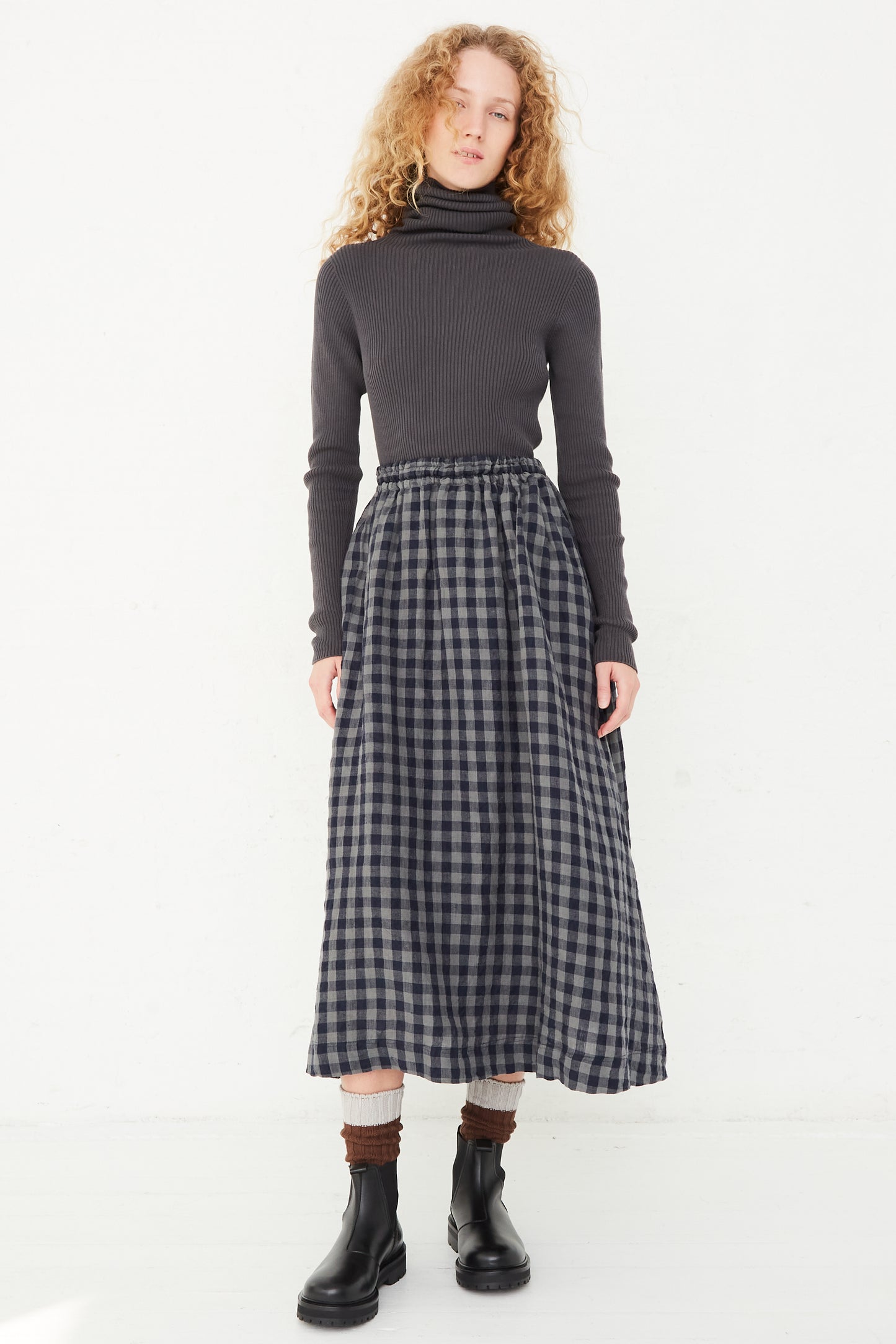 The model is wearing an Azumadaki Linen Gingham Skirt in Charcoal by Ichi Antiquités with an elasticated waist.