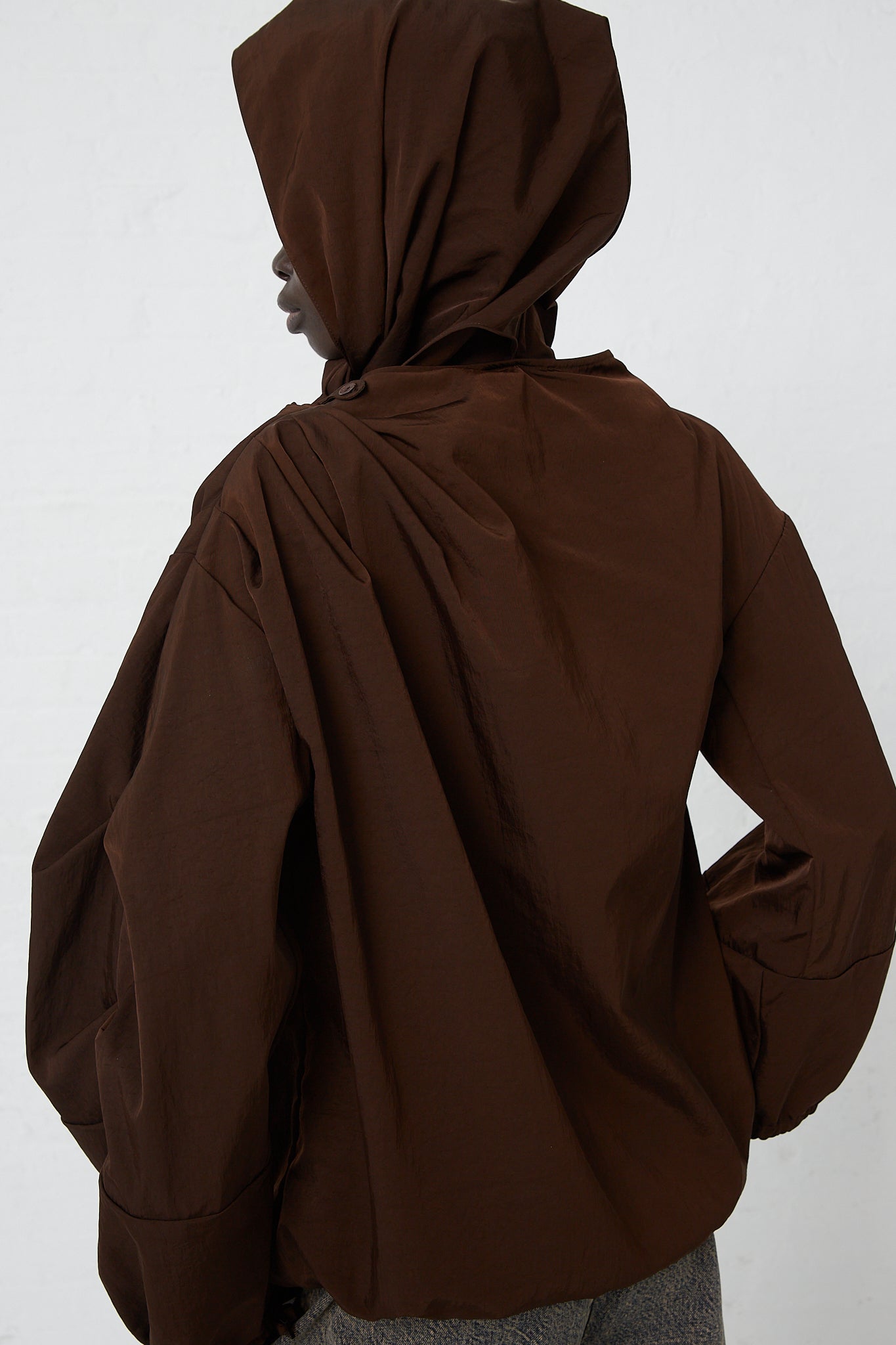 A woman wearing a Zipped on Sleeve Rain Blouse in Choco by Veronique Leroy made of waterproof taffeta nylon fabric.