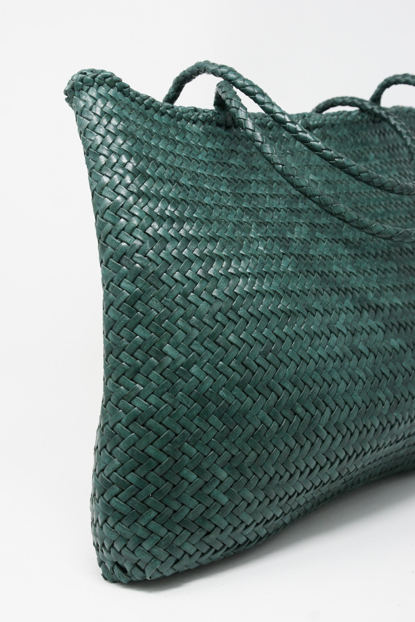 A Sophie Large Tote Bag in Forest by Dragon Diffusion, with braided handles, on a white surface.