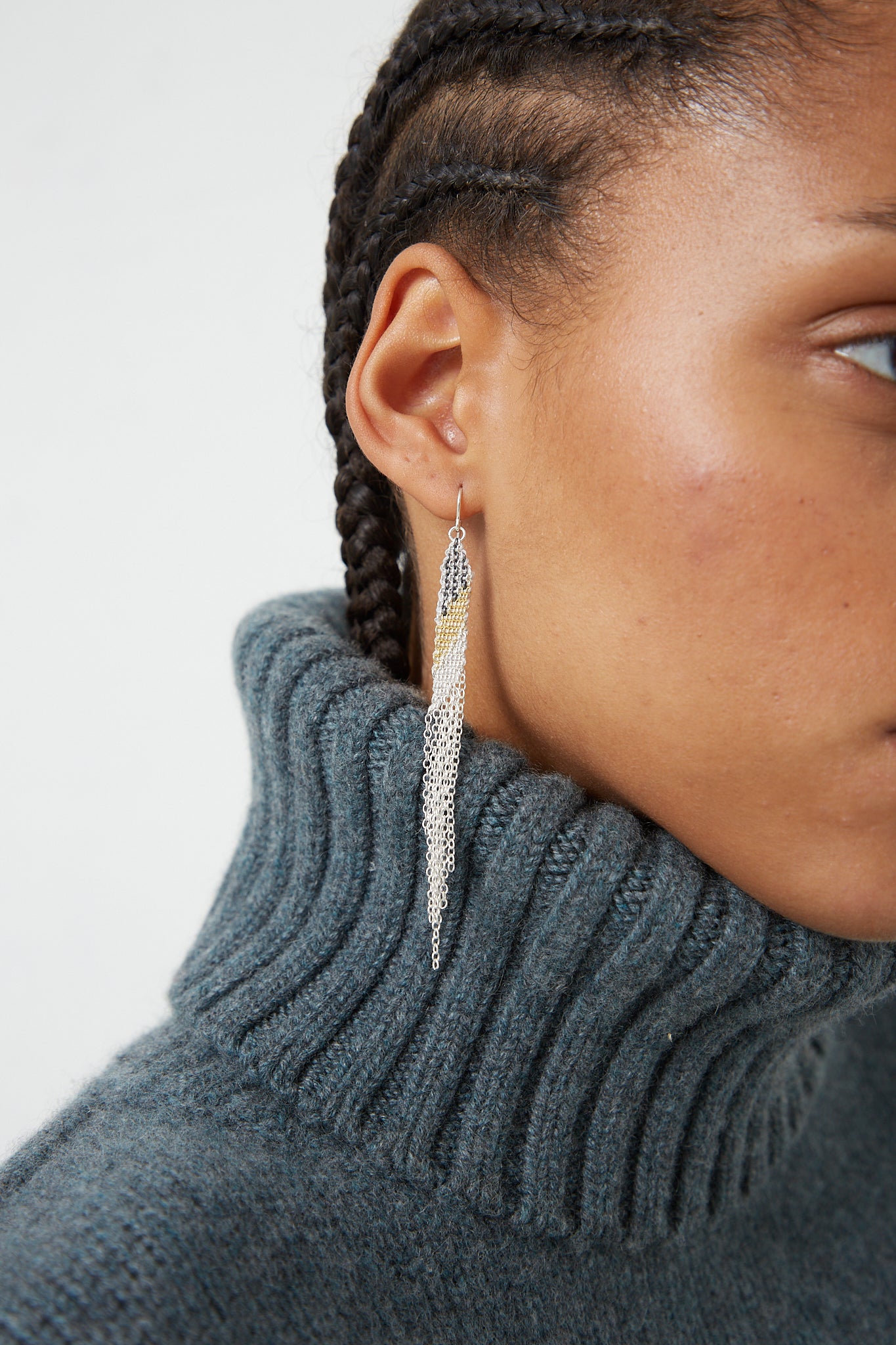 A woman wearing a grey sweater and Stephanie Schneider's Sterling Silver Earrings in Silver Oxidized and Gold-Plated Silk.