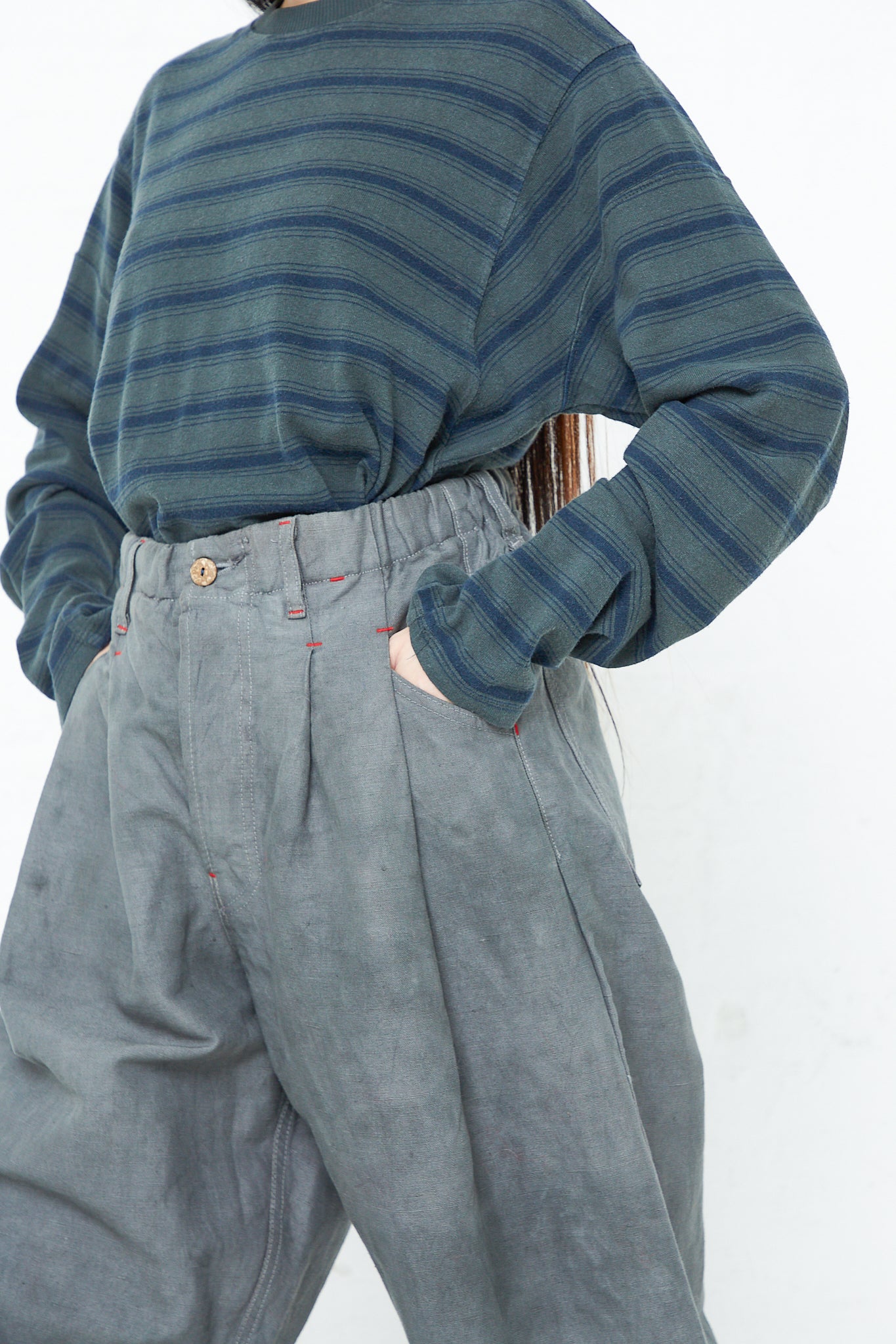 A woman wearing the Dr. Collectors P40 Z Boys Military Pant in Swiss Army, a 9 oz. Cotton and Hemp pant with a relaxed fit, pleats, and an elasticated waistband.