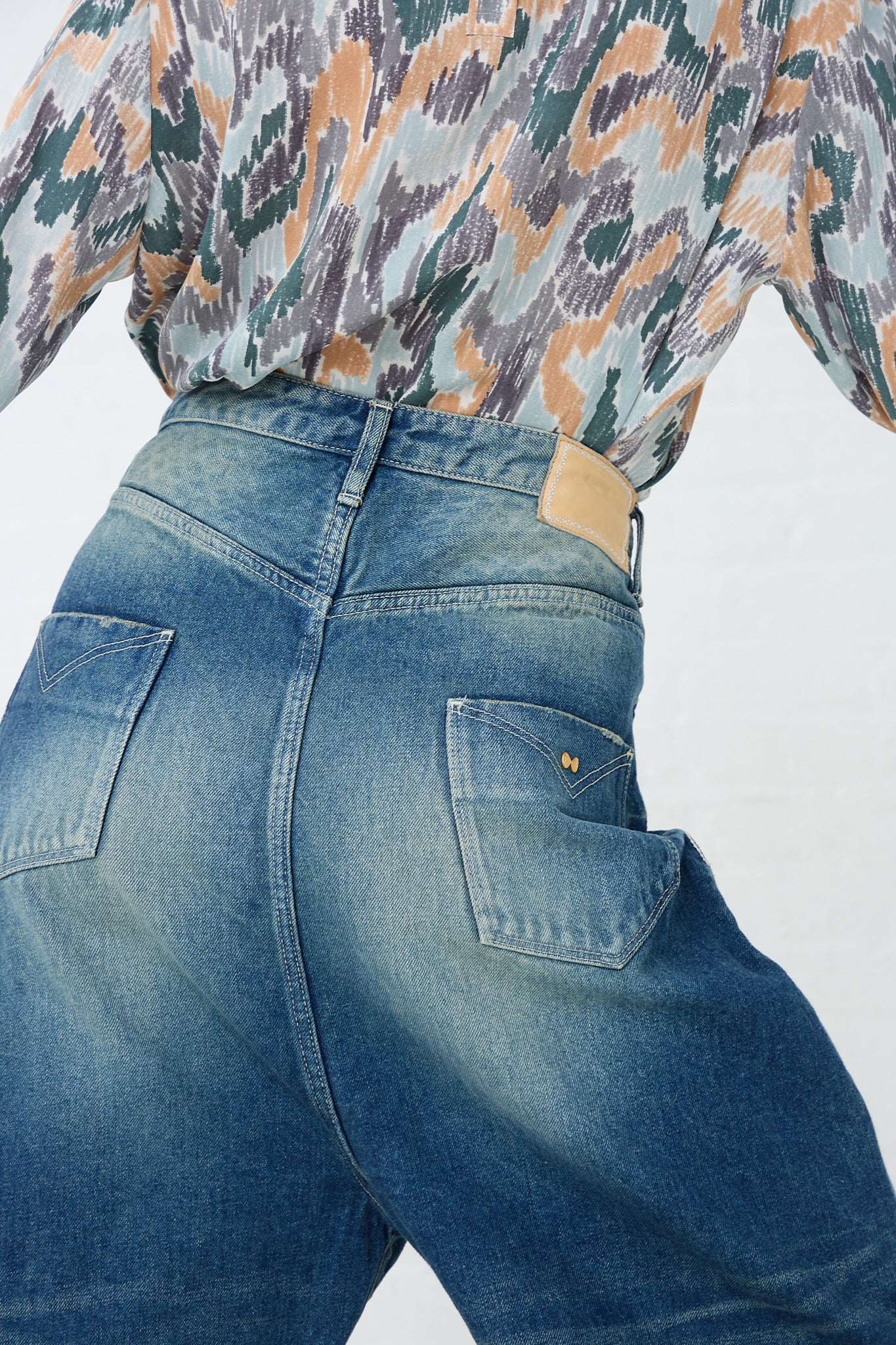 A woman is wearing a pair of Mina Perhonen Always New Tapered Pant in Blue denim shorts. Back view and up close highlighting back pockets and design details.