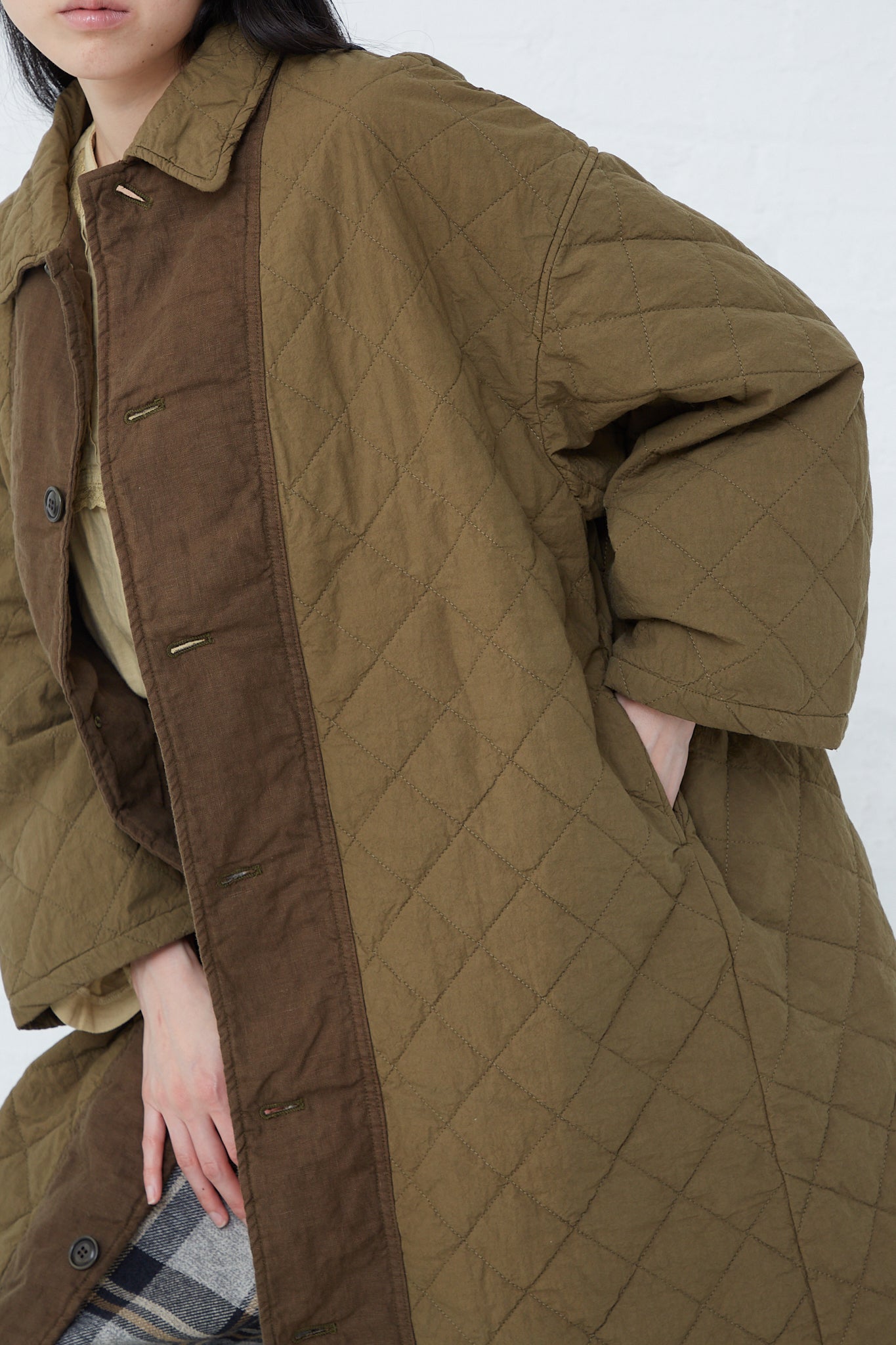 A woman wearing a nest Robe Cotton Ramie Quilted Long Coat in Olive.