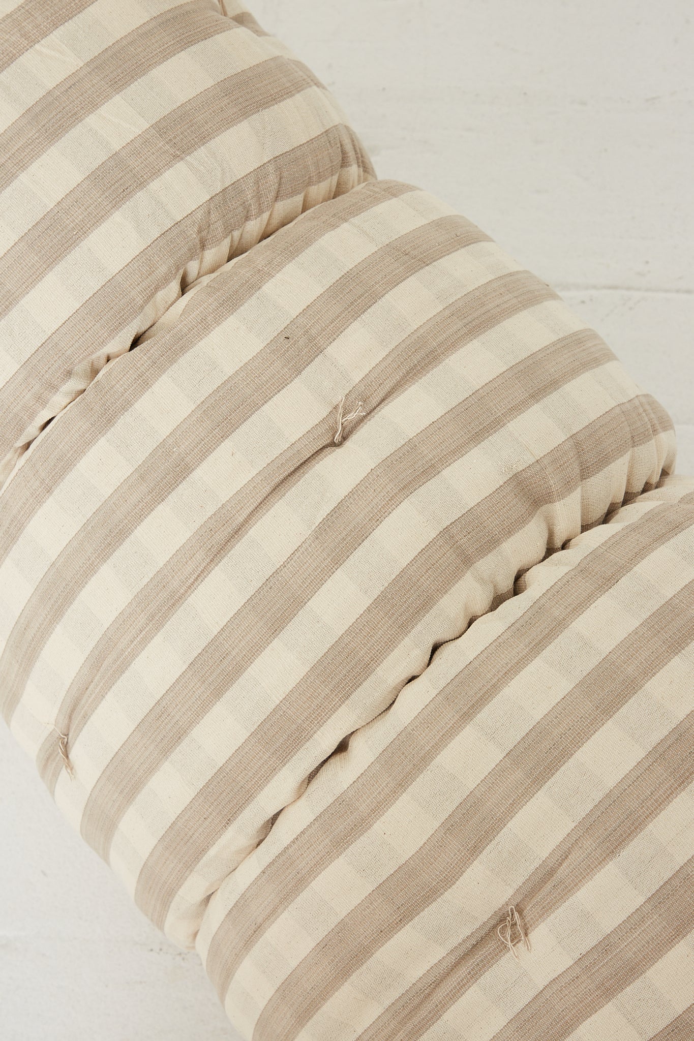 A lightweight Tufted Overlay Mattress in Greige and Off White Gingham pattern resting on a wooden floor by Tensira.