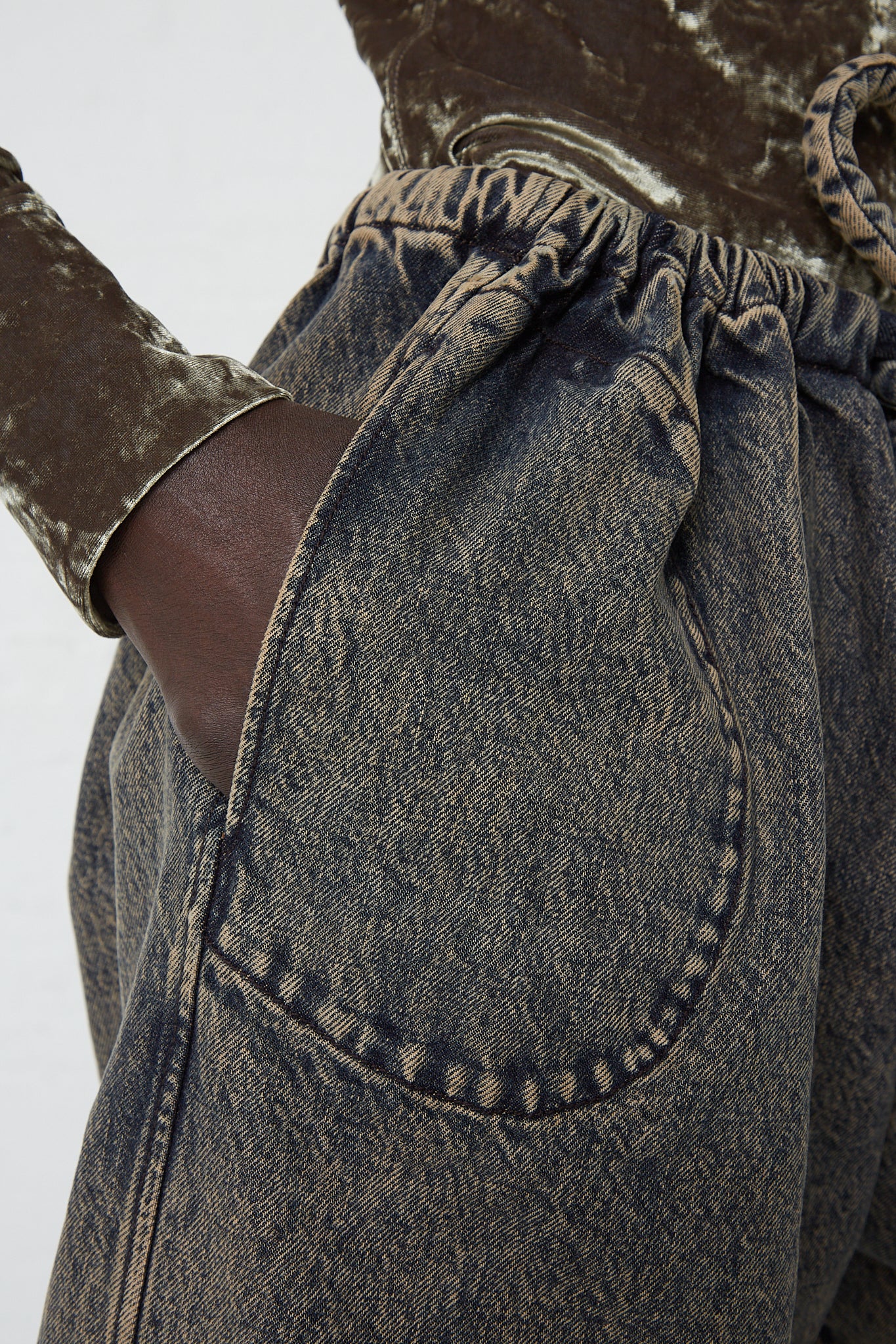 A close up of a woman wearing Veronique Leroy's Denim Belted Trousers in Acid Wash Denim with pockets.