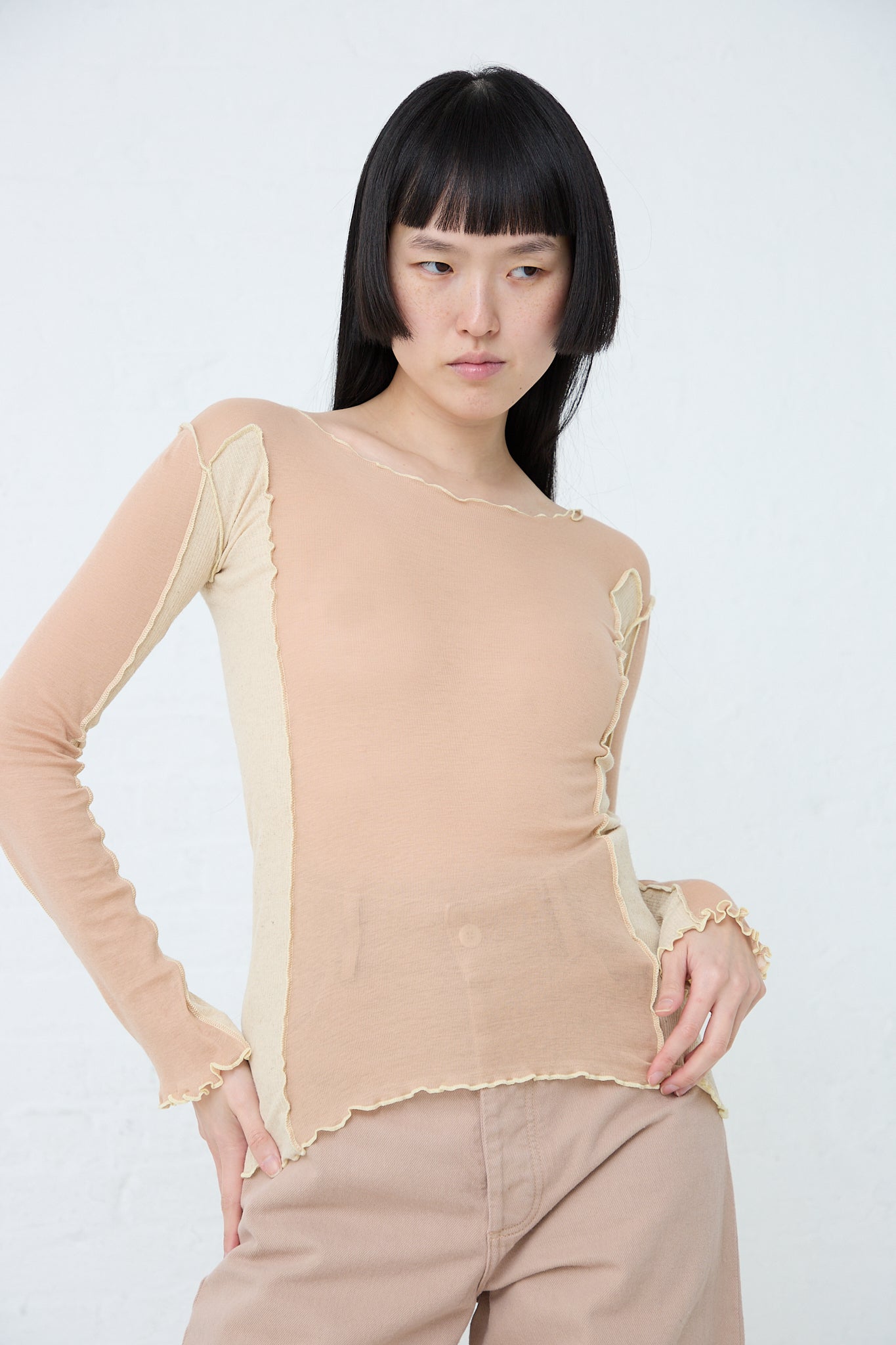 A model wearing a sustainably produced Sun Longsleeve in Rosy Camel top made of organic cotton and khaki pants. Brand: Baserange. Front view. 