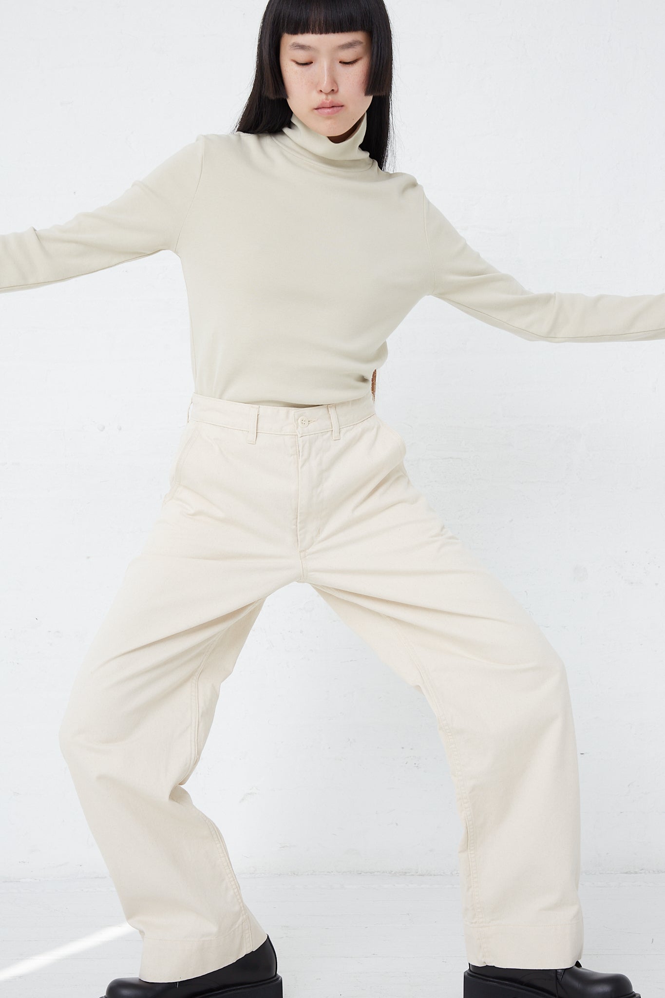 A woman wearing As Ever's 51 Chino in Natural pants with a turtleneck.