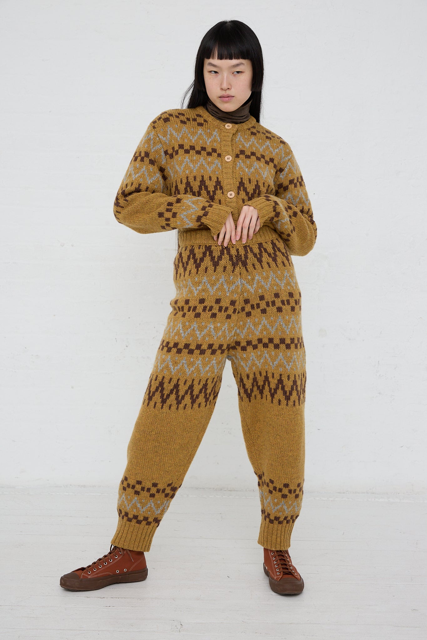 A woman in an Ichi Knit Pant in Camel jumpsuit posing in front of a white wall.