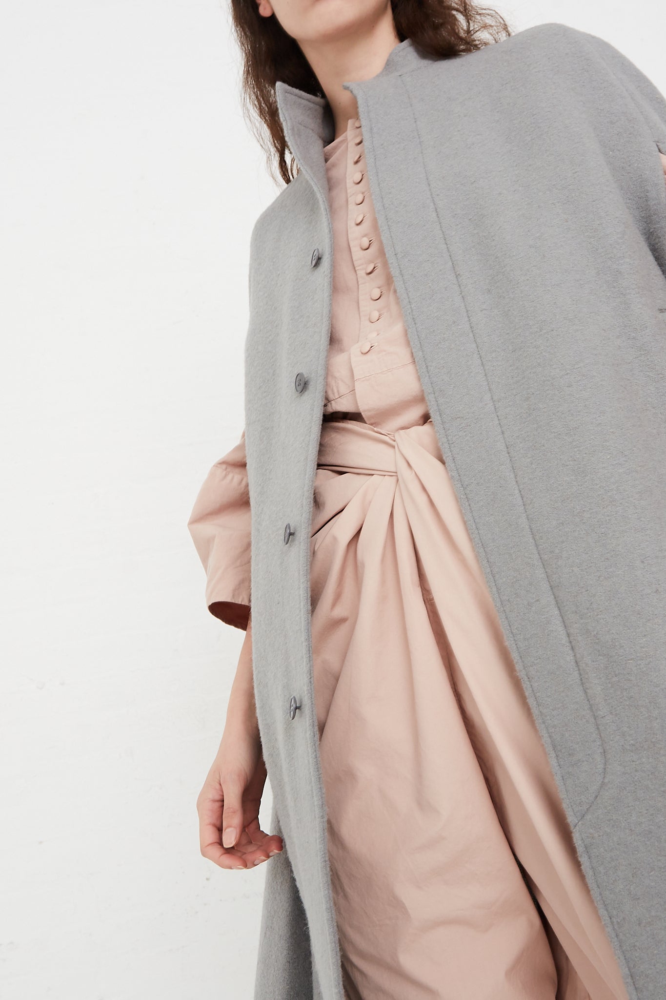 A model wearing a Japanese Suffolk Melton Cloak in Grey by Cosmic Wonder and pink pants.