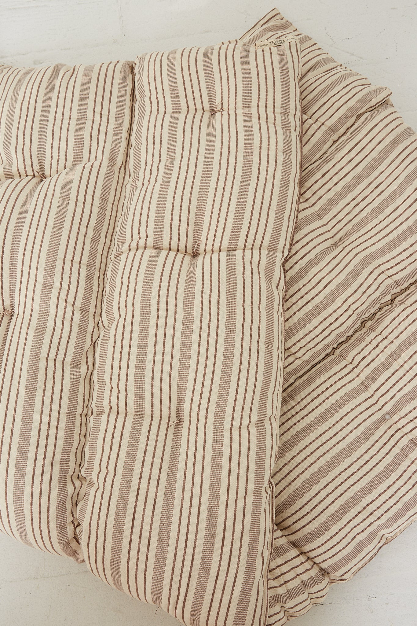 A Tensira Tufted Overlay Mattress in Chocolate Brown and Off White Stripe mattress folded.