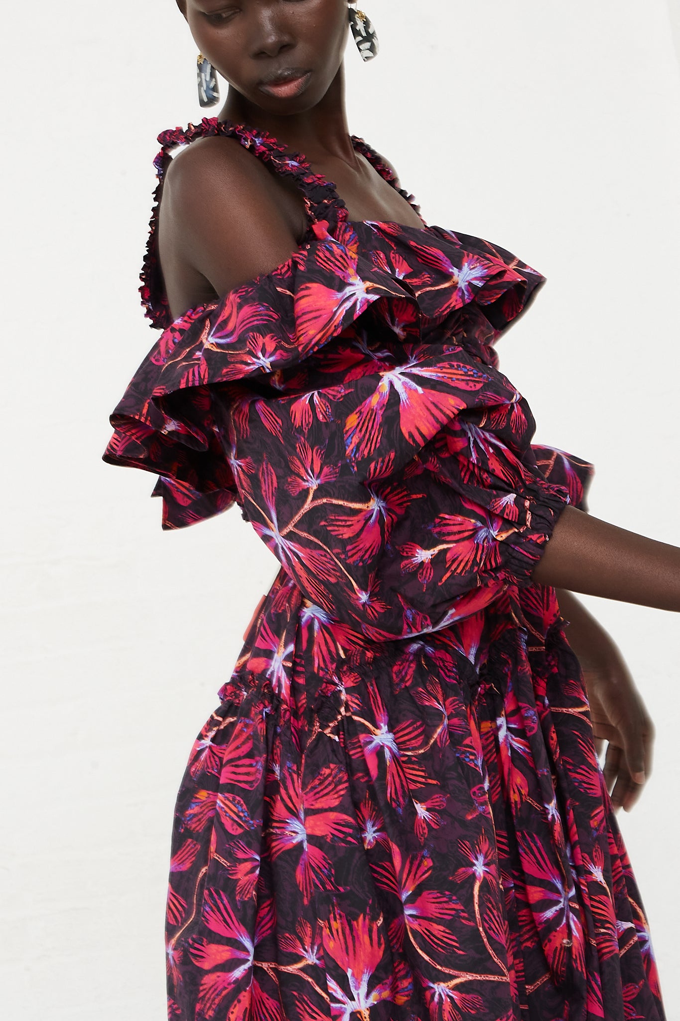 The model is wearing an Ulla Johnson Caprice Midi Dress in Zinnia, featuring vivid shades of magenta and hyacinth.