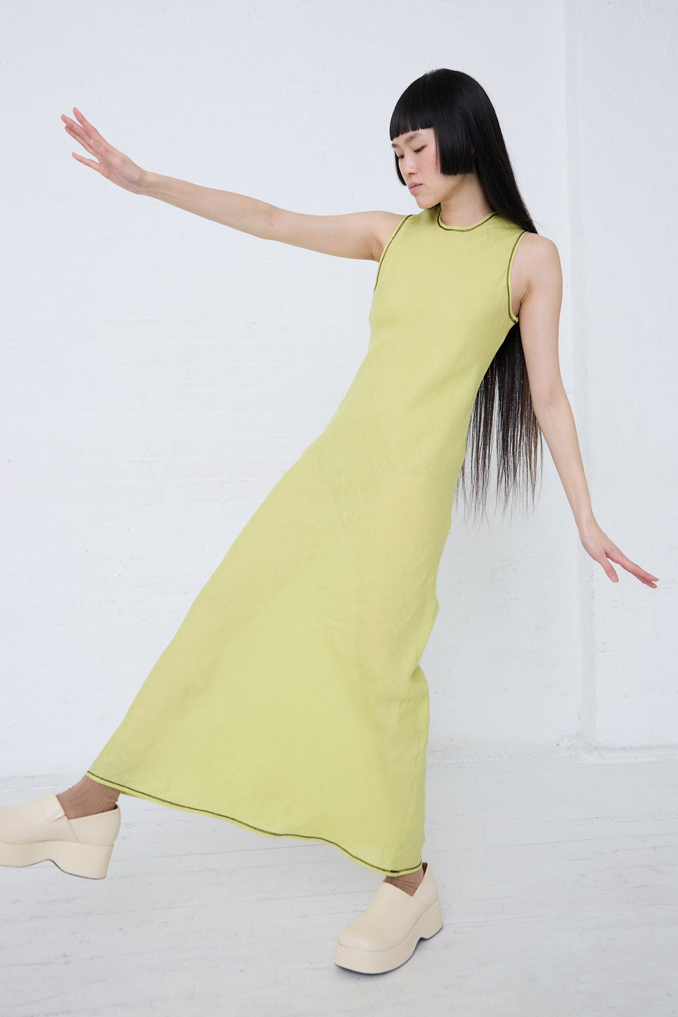 A woman in a Baserange Linen Dydine Tank Dress in Lime is dancing.