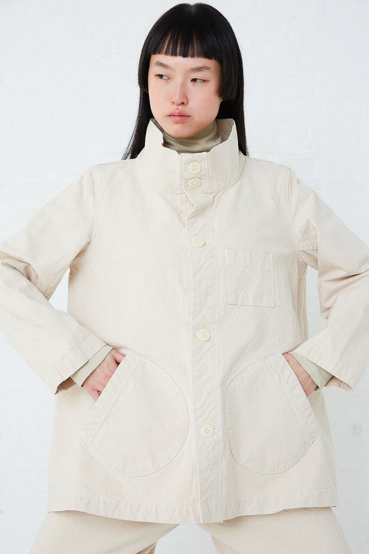 A model wearing a white Jesse Kamm Organic Canvas Deck Jacket in Natural and pants made from organic cotton.